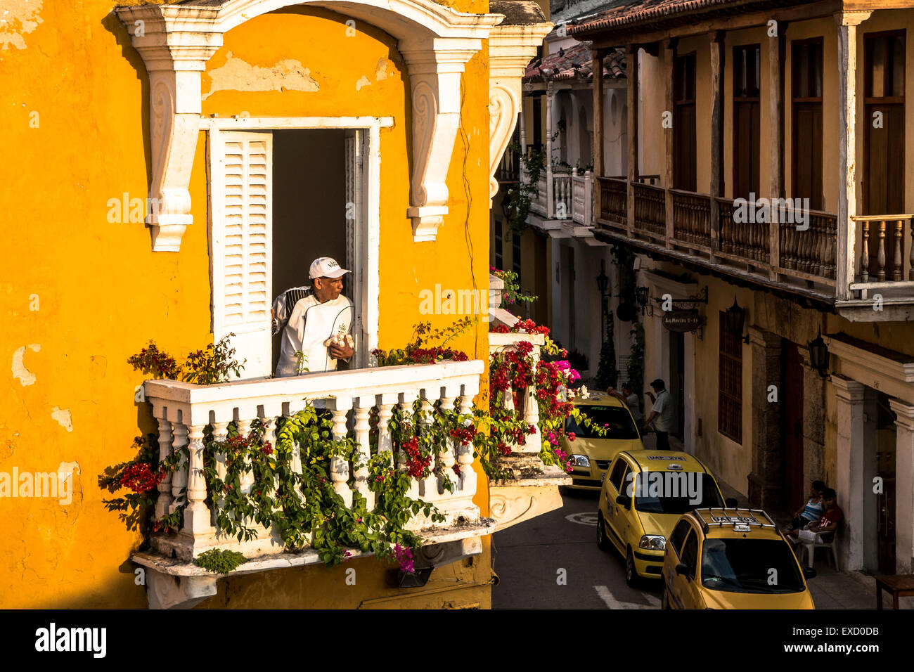 Ein Afro-Latino-Mann blickt vom Balkon eines kolonialen Erbes, das Gebäude in der Ciudad Vieja oder die Altstadt von Cartagena, Kolumbien Stockfoto