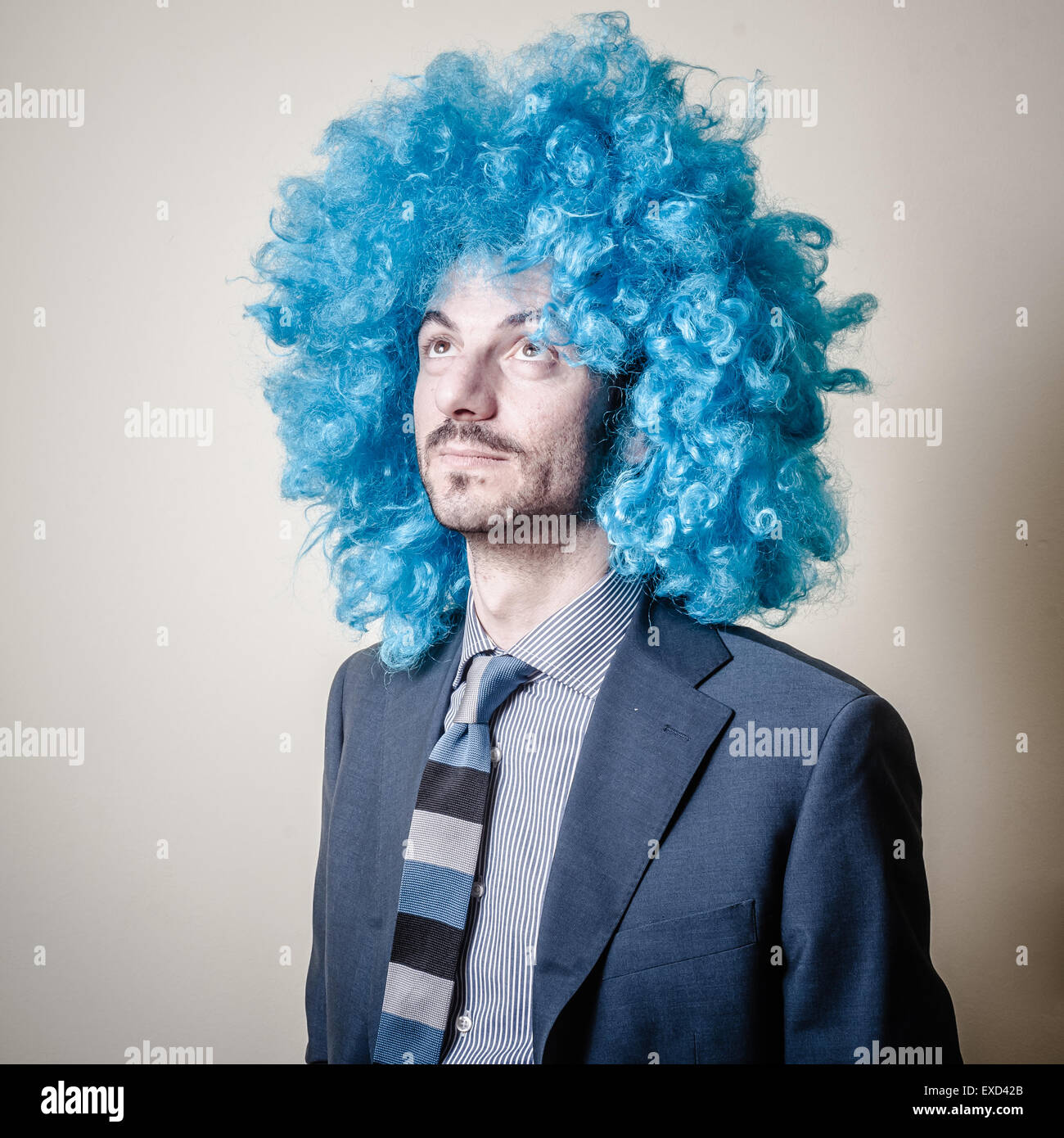 lustige Geschäftsmann mit blauen Perücke auf grauem Hintergrund Stockfoto