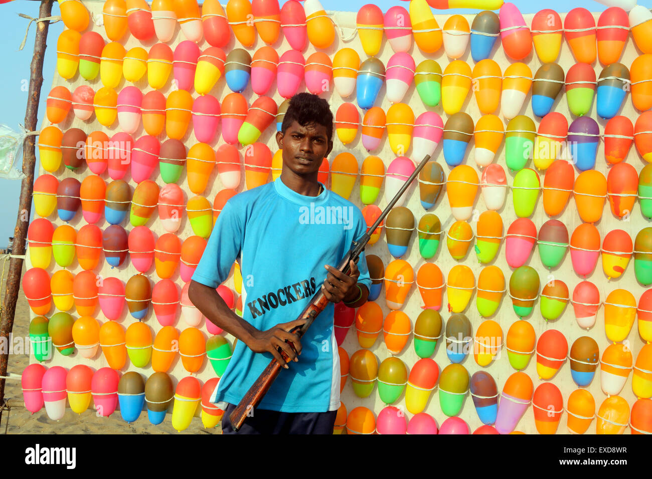 Ein junger Indianer hält ein Luftgewehr am Beach Fun Stand mit Ballonzielen in Chennai, Indien Stockfoto