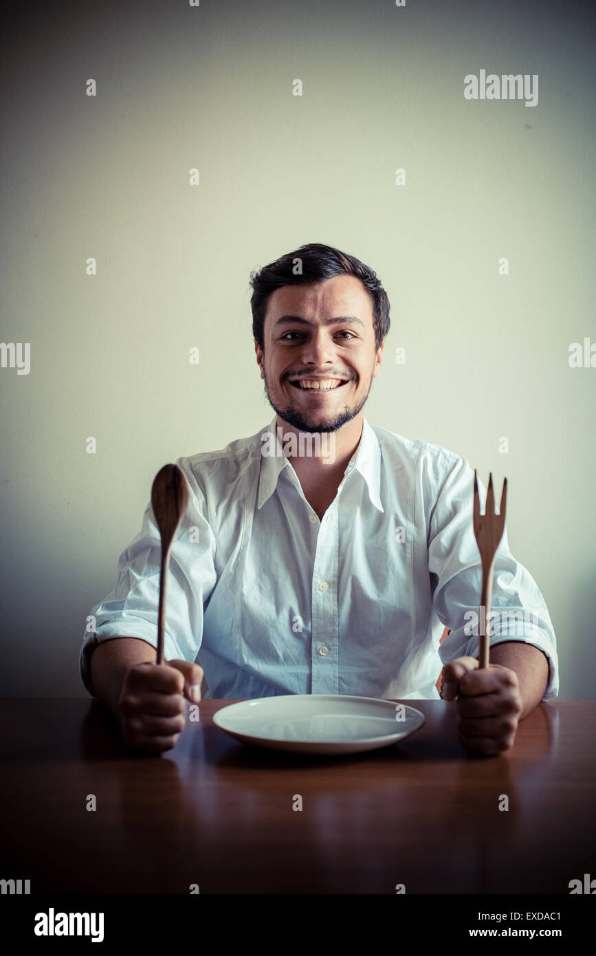 stilvolle Jüngling mit weißem Hemd in Mahlzeiten hinter dem Tisch essen Stockfoto