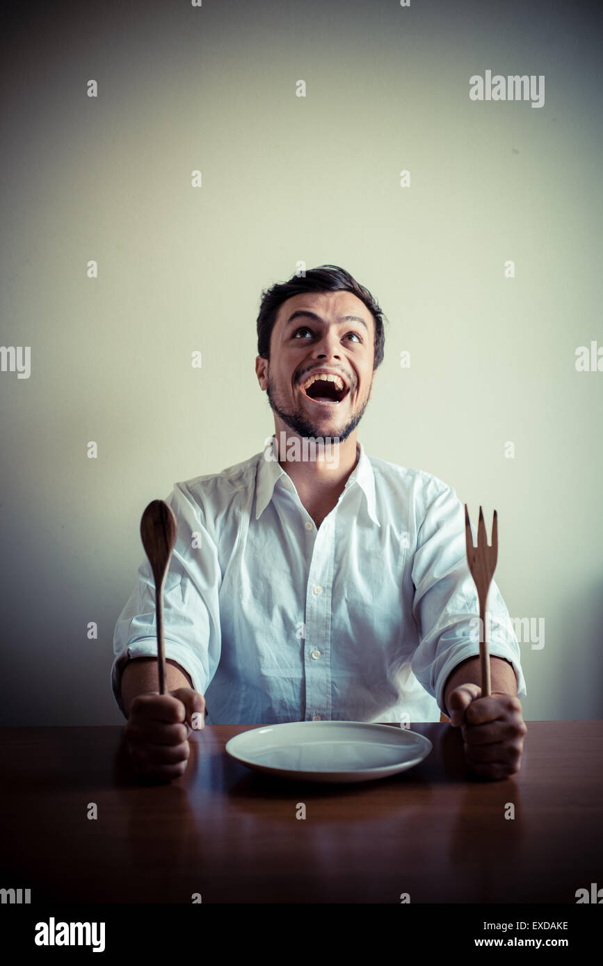 stilvolle Jüngling mit weißem Hemd in Mahlzeiten hinter dem Tisch essen Stockfoto