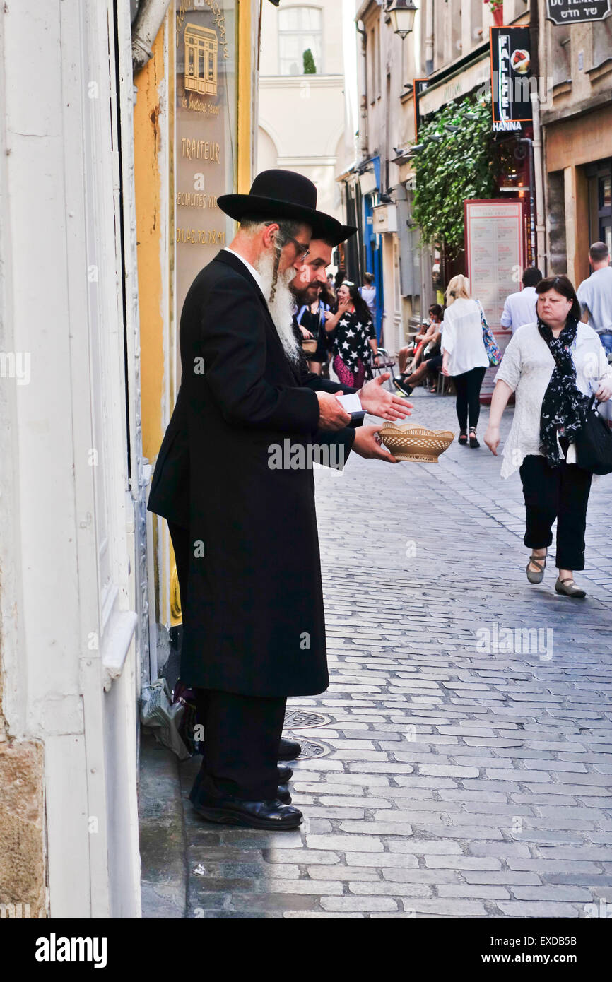 Zwei orthodoxe jüdische Männer lesen Torah, in das jüdische Viertel Le Marais, Paris, Frankreich um Spenden bitten. Stockfoto