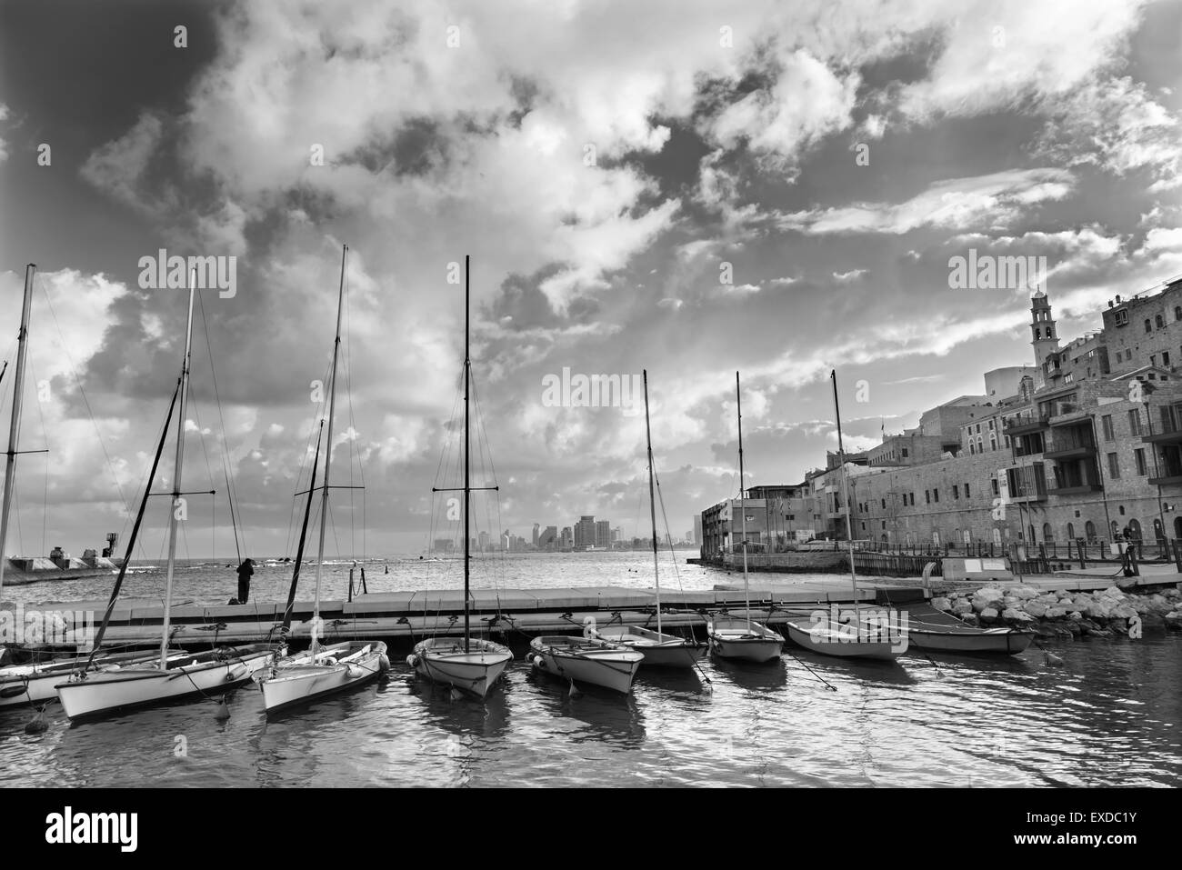 Tel Aviv - der kleine Hafen und Yachten unter alten Jaffa und Tel Aviv in der Backgound im Morgenlicht und Mann beim Fischen. Stockfoto