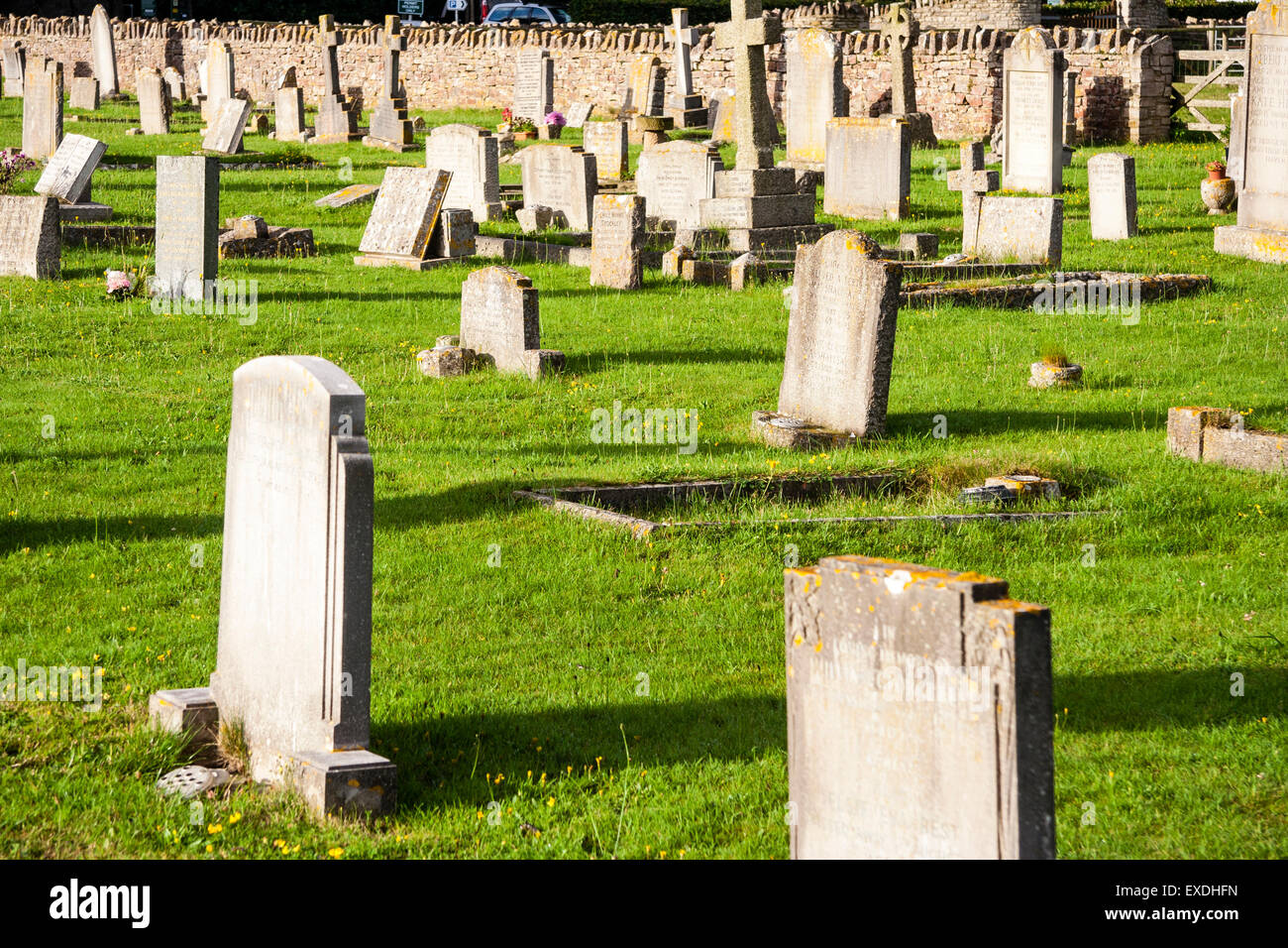 Englisch Friedhof am englischen Dorf Corfe, Dorset. Zeilen von Grabsteinen auf Gras leuchtet durch die frühe Morgensonne werfen lange Schatten. Stockfoto