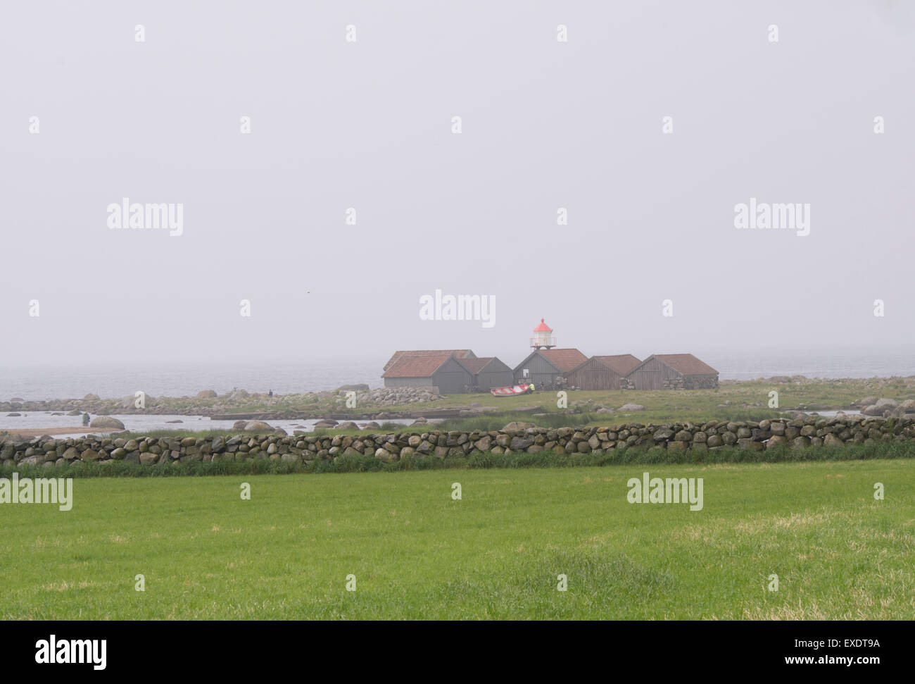 Nebel über der Nordsee Jæren Norwegen, Unschärfe, die der Horizont, Küste mit Leuchtturm, Bootshäuser Steinmauern und grauem Himmel Stockfoto