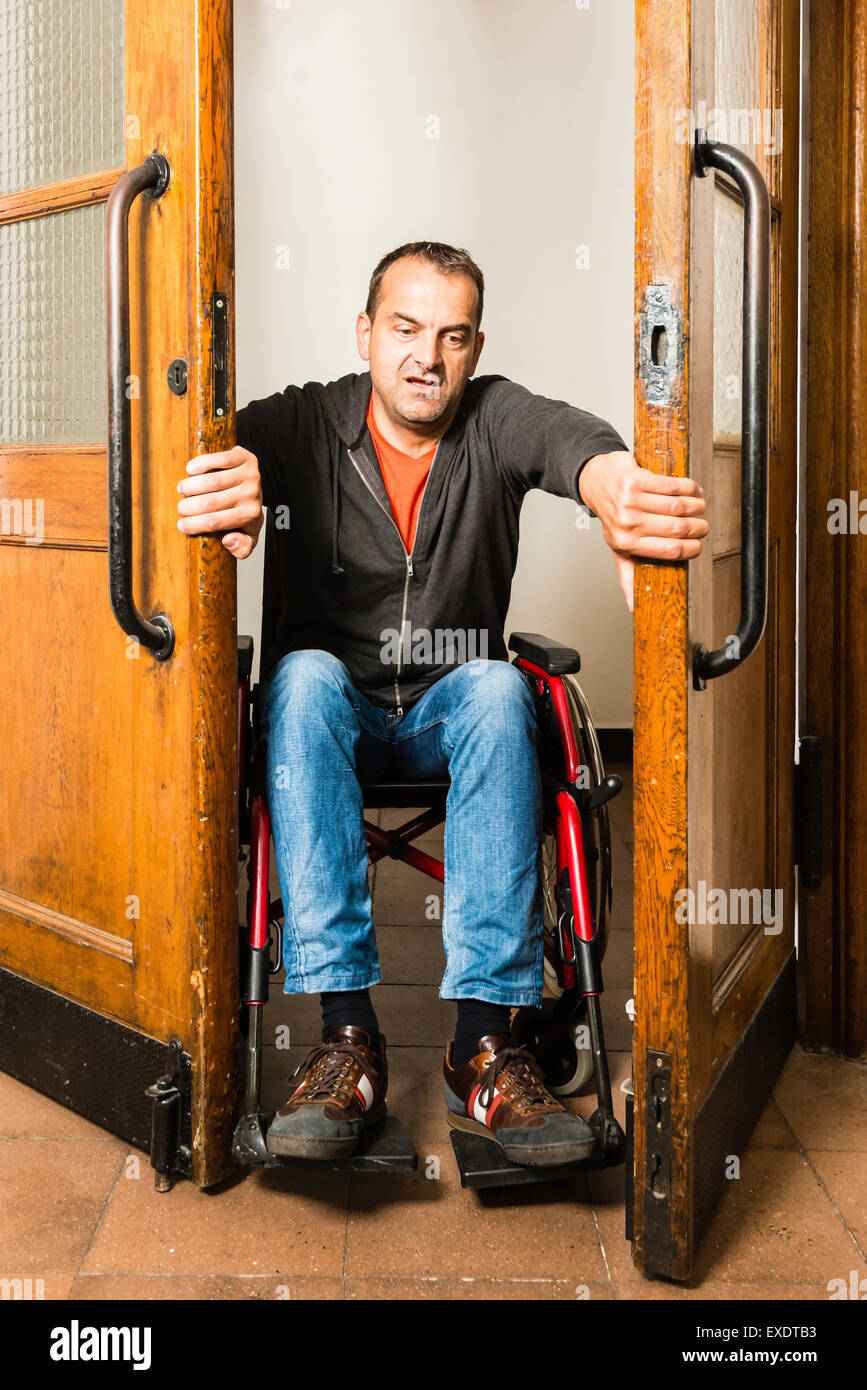 Mann im Rollstuhl stecken zwischen Pendeltüren Stockfoto