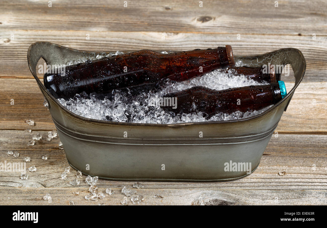 Vintage Metall-Wanne geformt Eimer gefüllt mit zerkleinertem Eis und Flaschenbier auf urigen Holzbrettern. Stockfoto