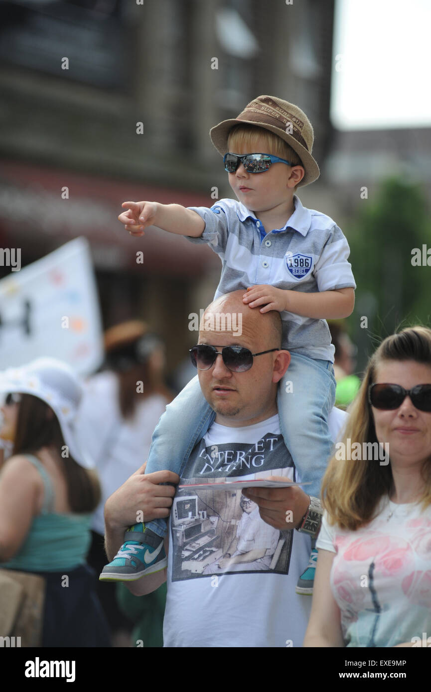 Ein Junge sitzt hoch auf seines Vaters Schultern gerade eine Parade. Bild: Scott Bairstow/Alamy Stockfoto