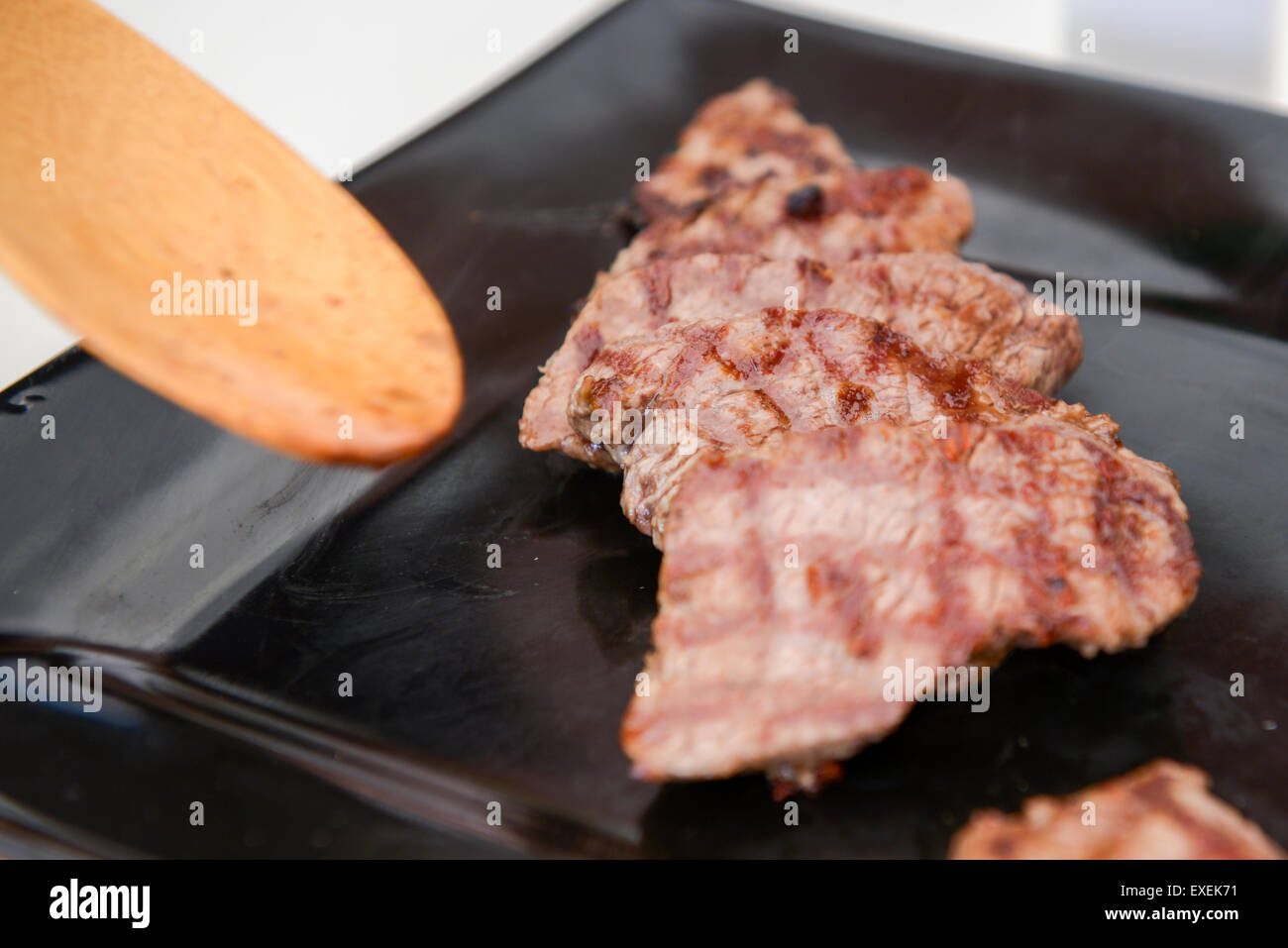 Köstliches saftiges Steak auf einer schwarzen quadratischen Platte Stockfoto