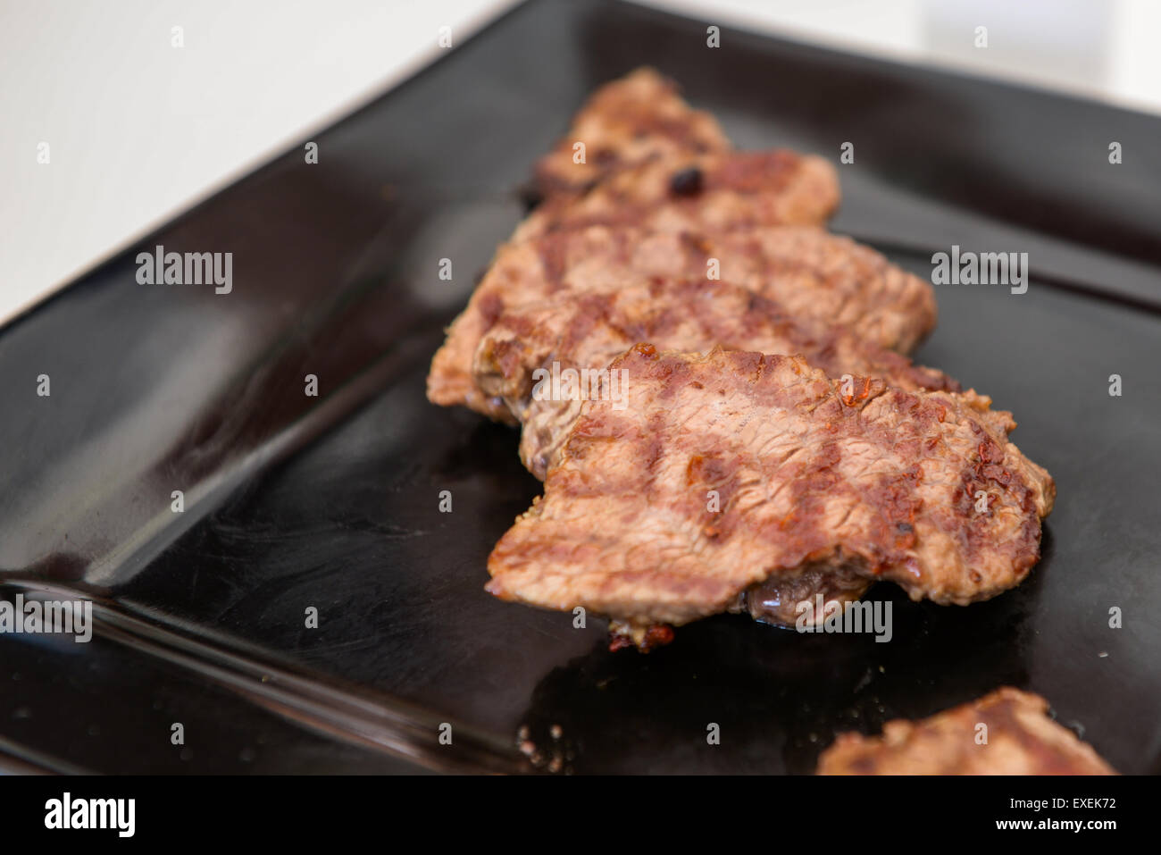 Köstliches saftiges Steak auf einer schwarzen quadratischen Platte Stockfoto