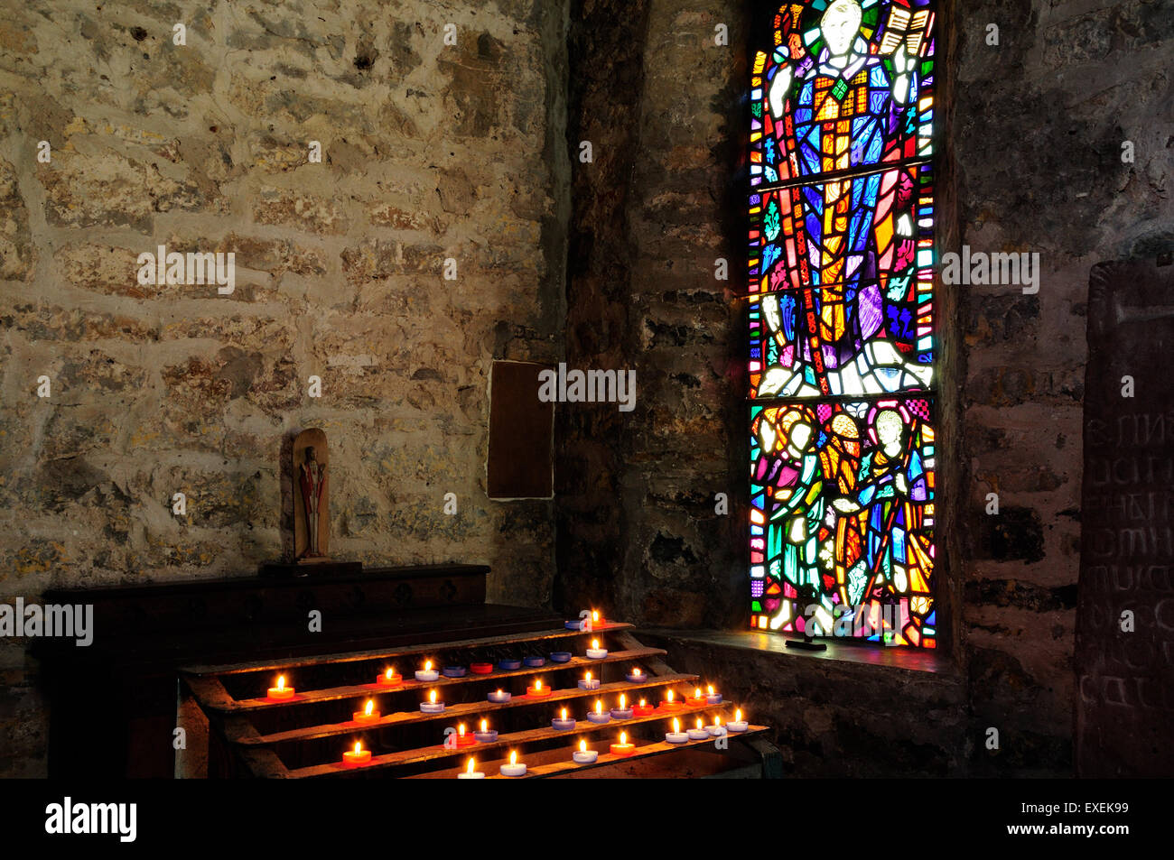 Beleuchtet, brennende Votivkerzen und Glasfenster St. Illtyds Kirche der alten Priorat Caldey Island Wales Stockfoto