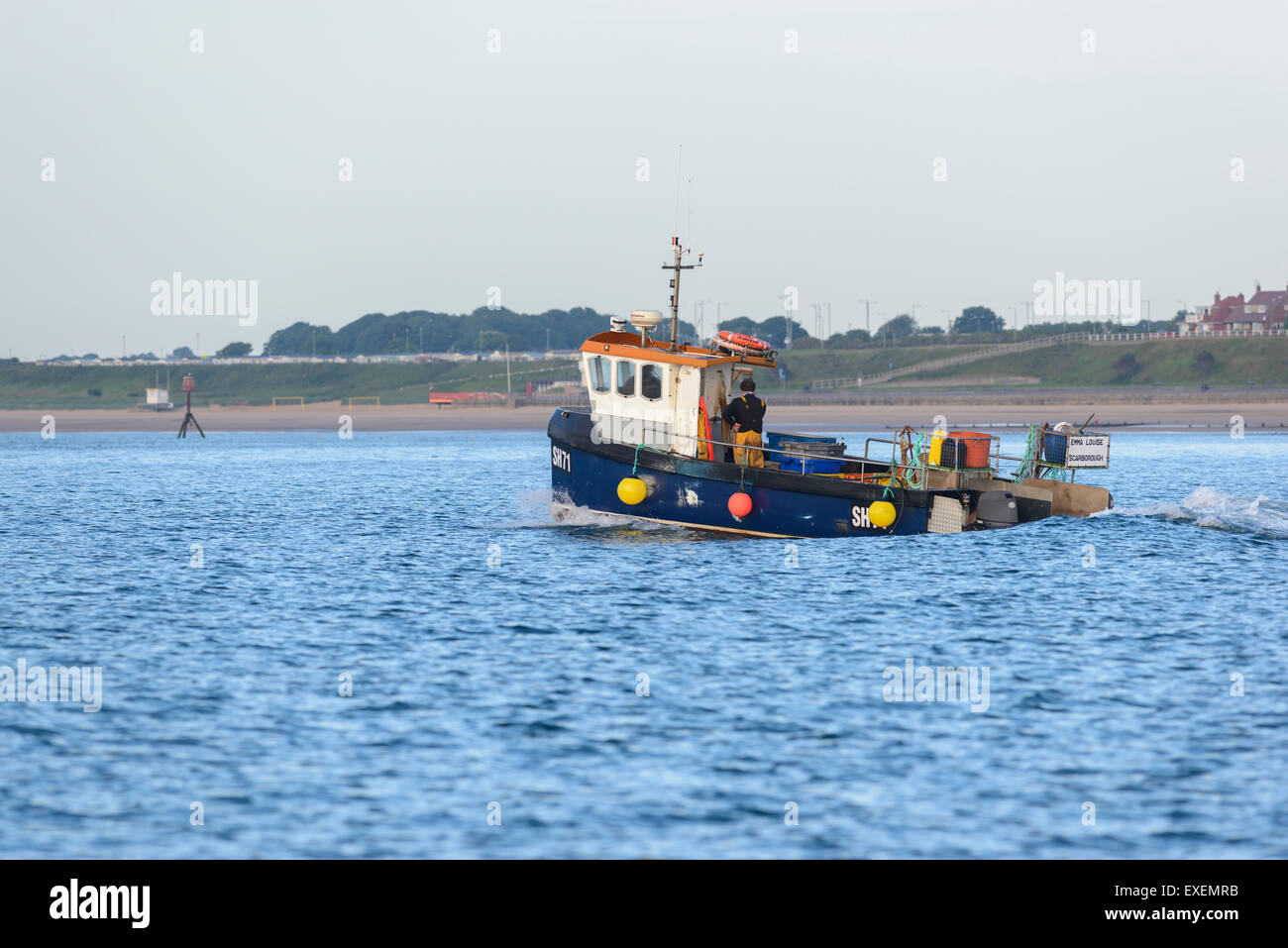 Ein Fischerboot Schiff Segeln aus Bridlington in den frühen Morgenstunden mit Bridlington Strand im Hintergrund Stockfoto