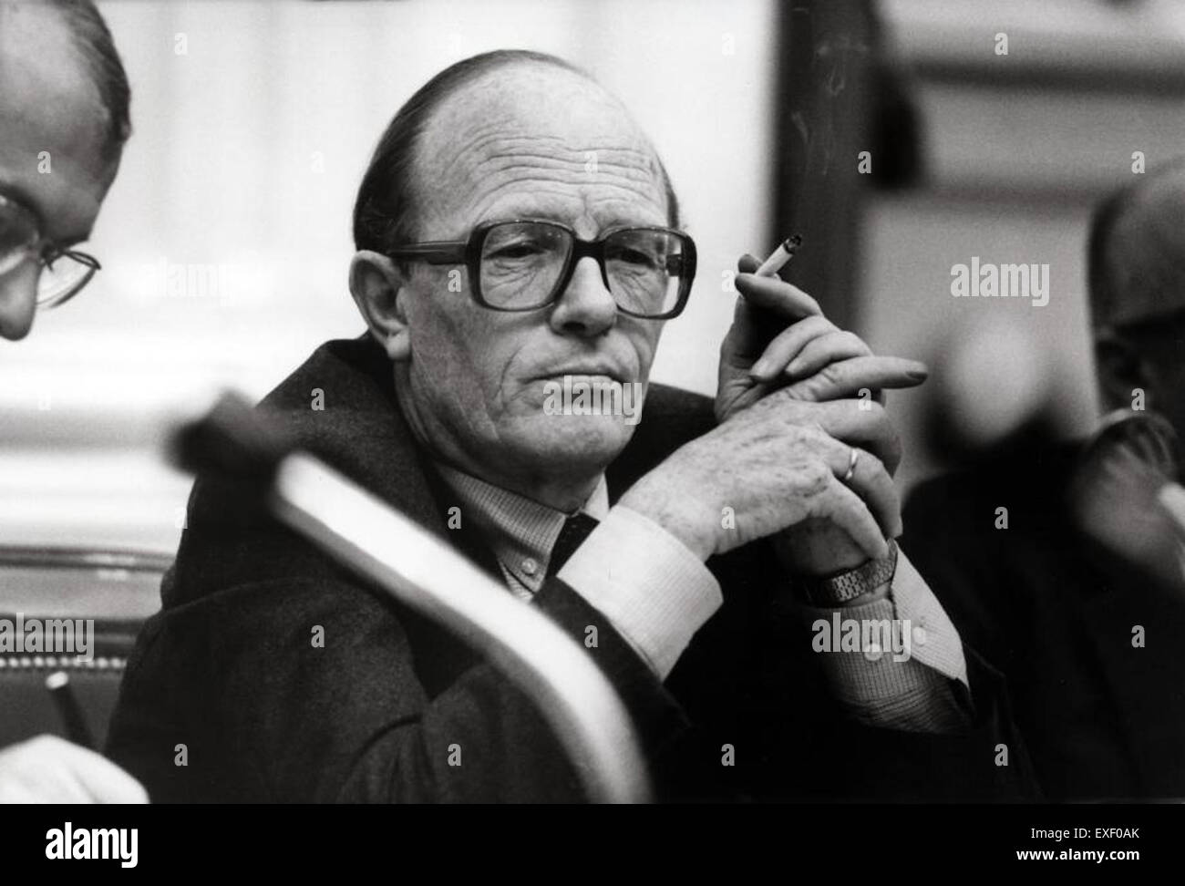 Dieses Foto zeigt Minister Rietkerk, der in der niederländischen Parlamentskammer raucht. Das Bild zeigt einen Moment im politischen Leben und spiegelt die informelle Atmosphäre der damaligen Zeit und die persönlichen Gewohnheiten von Persönlichkeiten des öffentlichen Lebens während der Parlamentssitzungen wider. Stockfoto
