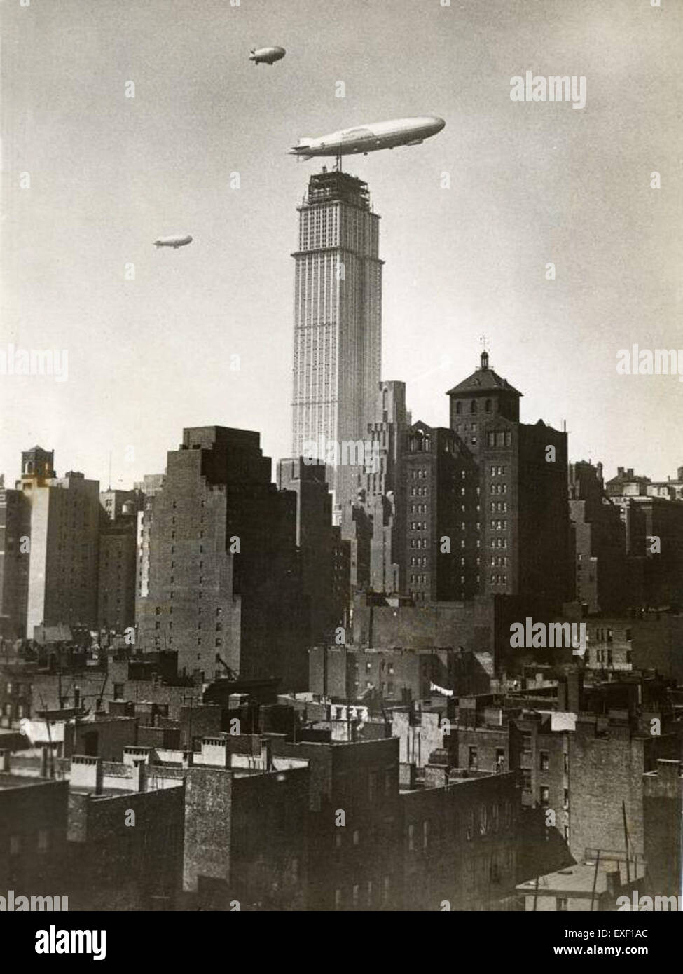 Dieses historische Foto zeigt einen Zeppelin, der während seines Baus in der Nähe des Empire State Building fliegt. Das Bild bildet einen markanten Kontrast zwischen dem futuristischen Luftschiff und dem architektonischen Wunderwerk des frühen 20. Jahrhunderts. Es steht für eine Ära des rasanten technologischen Fortschritts und ikonischer amerikanischer Wahrzeichen. Stockfoto