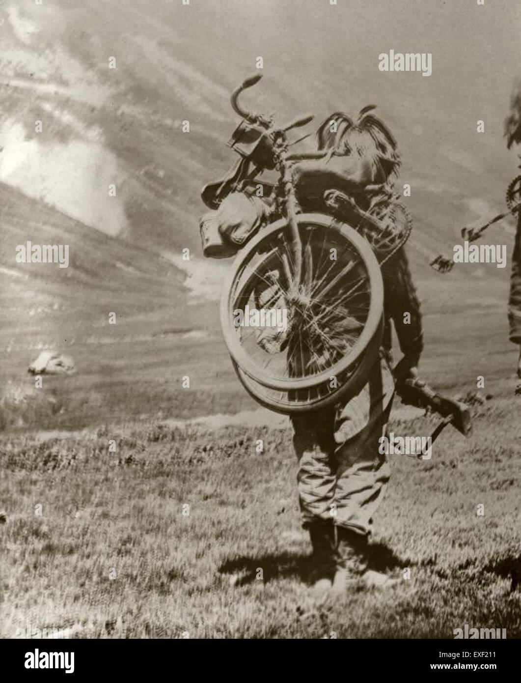 In diesem historischen Bild ist ein Soldat aus dem Ersten Weltkrieg mit seinem faltbaren Fahrrad dargestellt. Die Ausrüstung des Soldaten, einschließlich des Fahrrades, spiegelt die Zweckmäßigkeit und Mobilität wider, die während des Krieges benötigt werden. Stockfoto