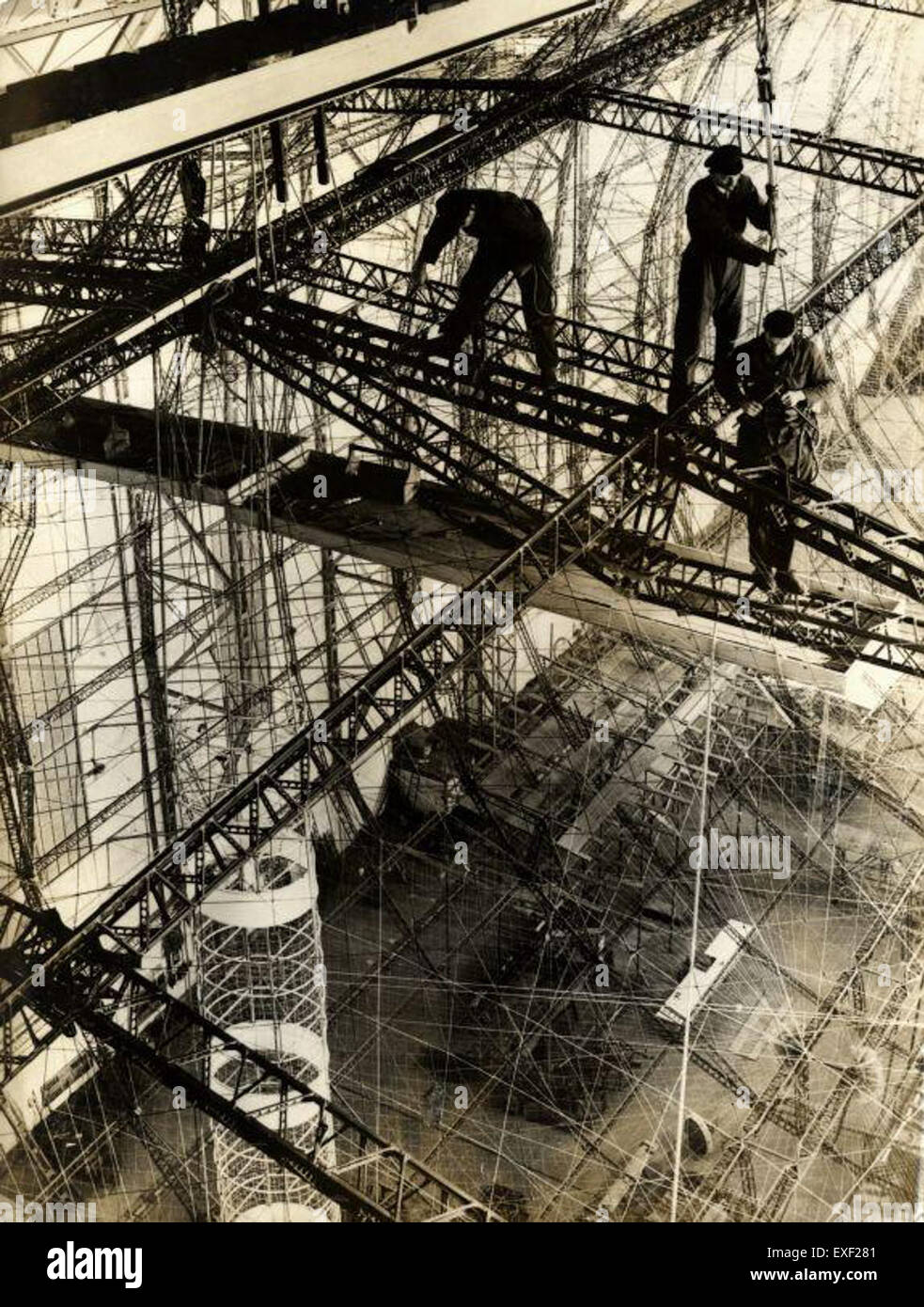 Dieses Bild zeigt Arbeiter in einer Zeppelin-Fabrik, die möglicherweise Teile eines Zeppelin-Luftschiffs zusammenbauen oder warten. Das Fabrikumfeld unterstreicht den industriellen Maßstab und den technologischen Fortschritt des frühen 20. Jahrhunderts. Stockfoto