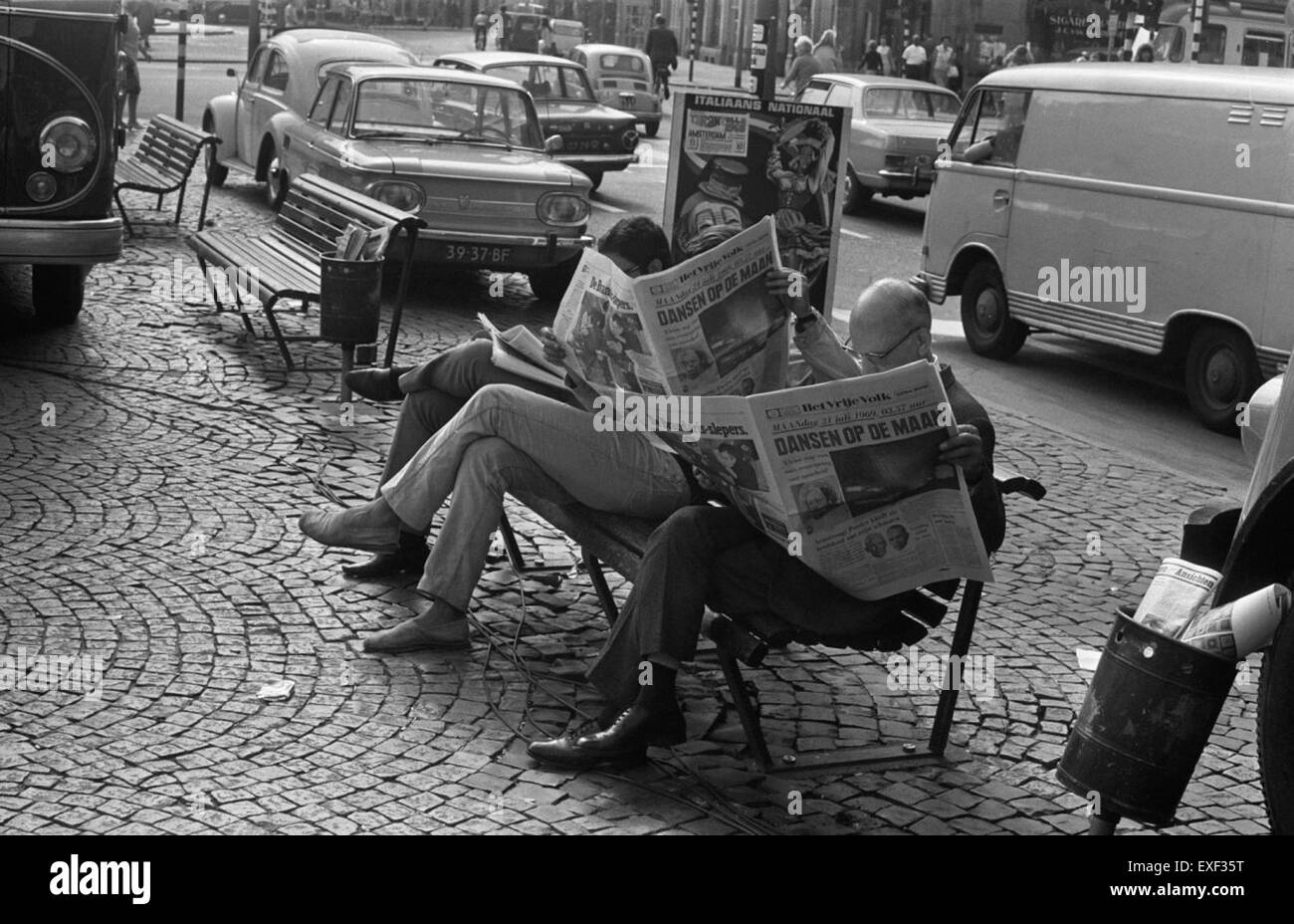 Ein Bild von der Mondlandung Apollo 11, mit Menschen auf der Erde, die die Zeitung lesen. Das Foto stellt das monumentale Ereignis der menschlichen Weltraumforschung dem Alltag gegenüber und betont, dass die Mondlandung ein historischer Moment war, der die globale Fantasie fesselte. Stockfoto