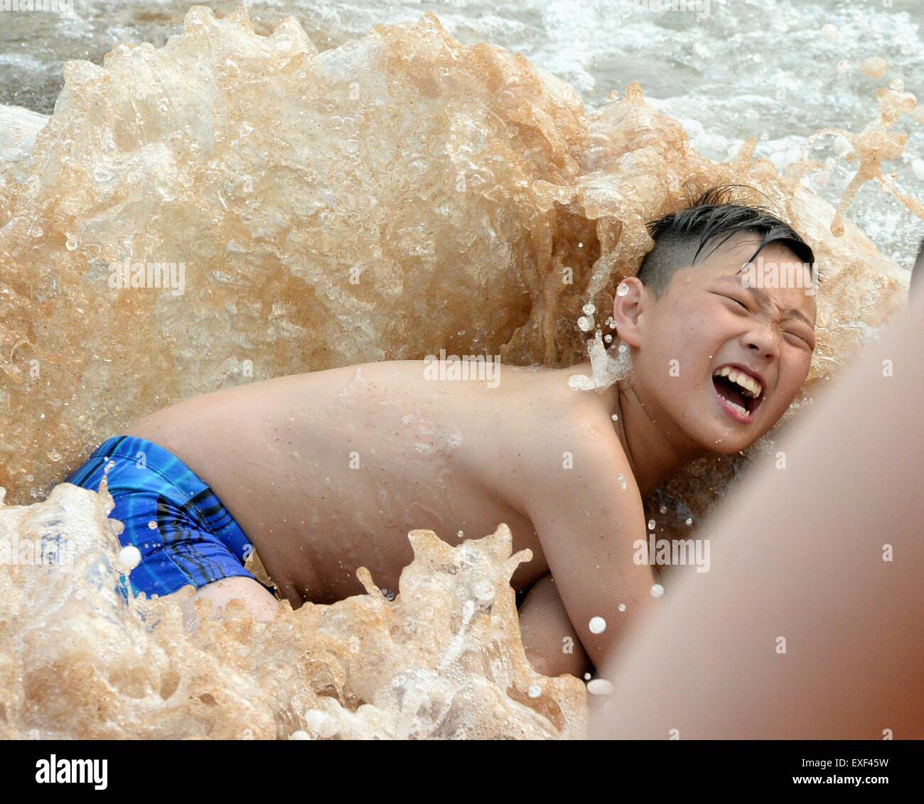 Qingdao, China Shandong Provinz. 13. Juli 2015. Ein Teenager hat Spaß an einem Strand in Qingdao, der ostchinesischen Provinz Shandong, 13. Juli 2015. Strände in Qingdao wurden Schwarm von Menschen in der Hitzewelle, die viele Teile im Nordchinas am Montag getroffen. Bildnachweis: Feng Jie/Xinhua/Alamy Live-Nachrichten Stockfoto