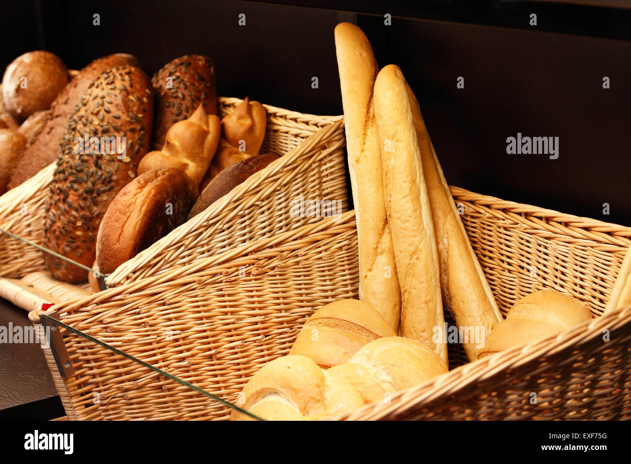 Körbe mit verschiedenen Arten von frisch gebackenem Brot auf dem Regal im Laden. Stockfoto