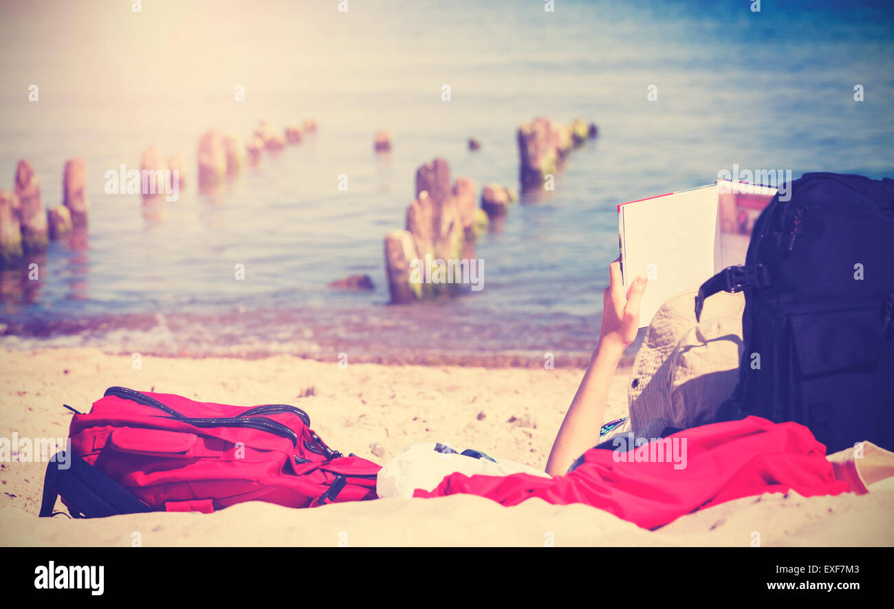 Vintage getönten Foto von unerkennbar Person liest Buch am Strand. Stockfoto