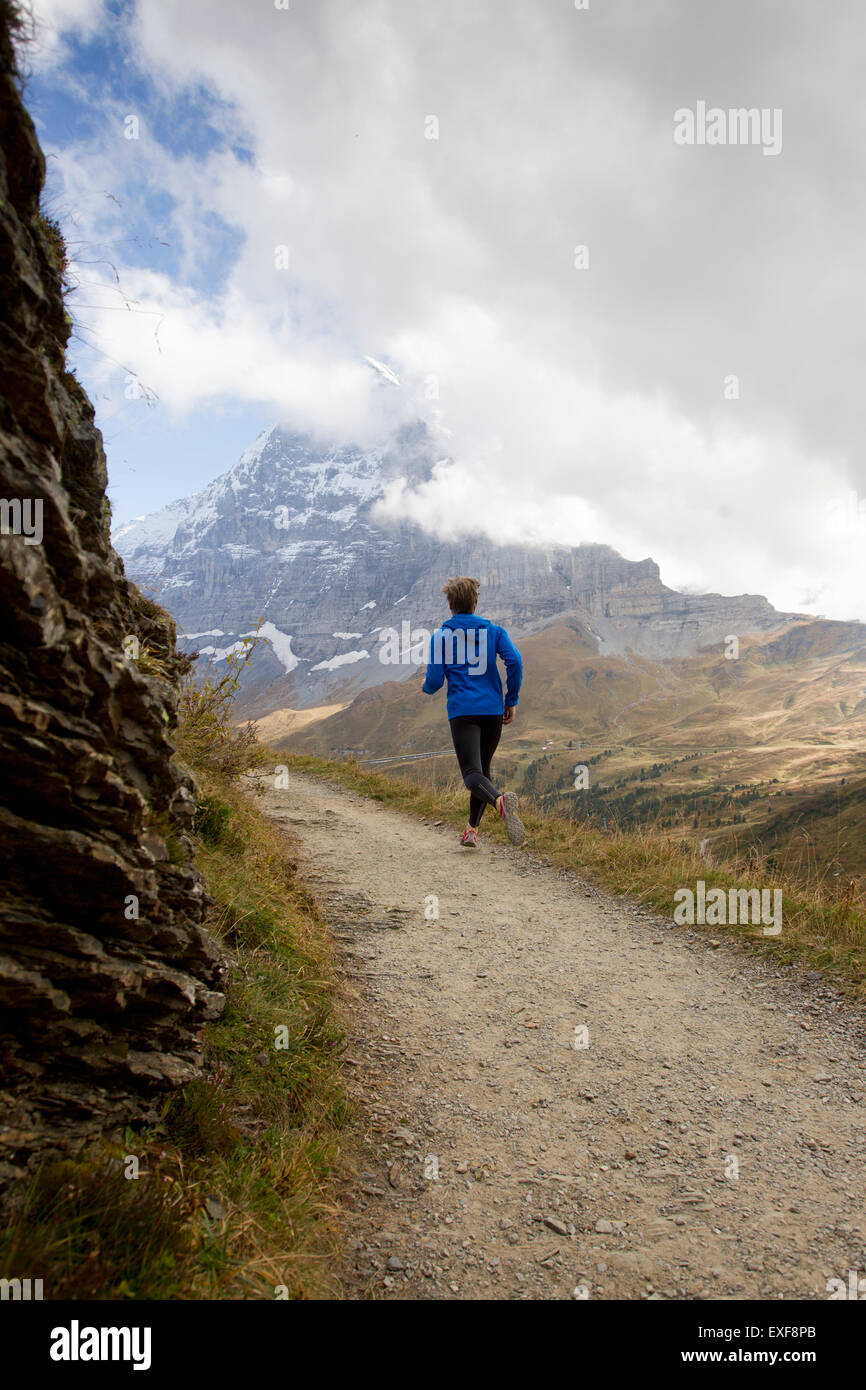 Rückansicht der Mann läuft auf Feldweg in Richtung Mount Eiger, Grindelwald, Schweiz Stockfoto