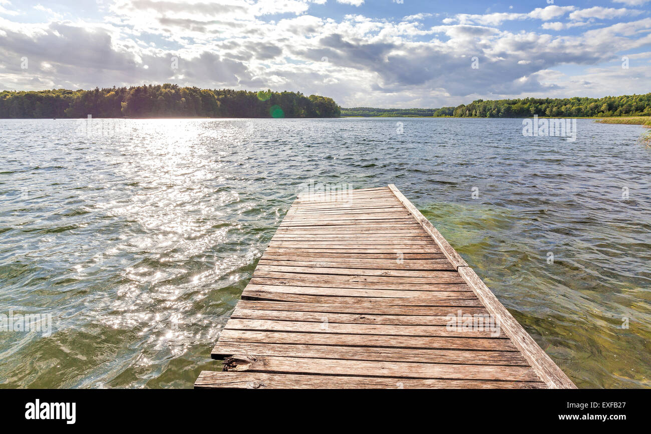 Alte hölzerne Pier am See mit Flare-Effekt, Ostromeck in Polen. Stockfoto