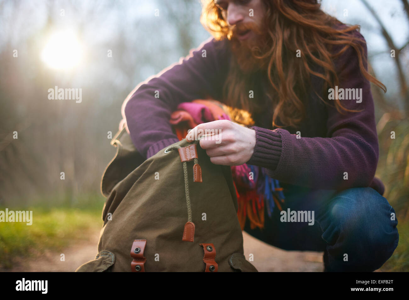 Mann kniet, Wühlen im Rucksack Stockfoto