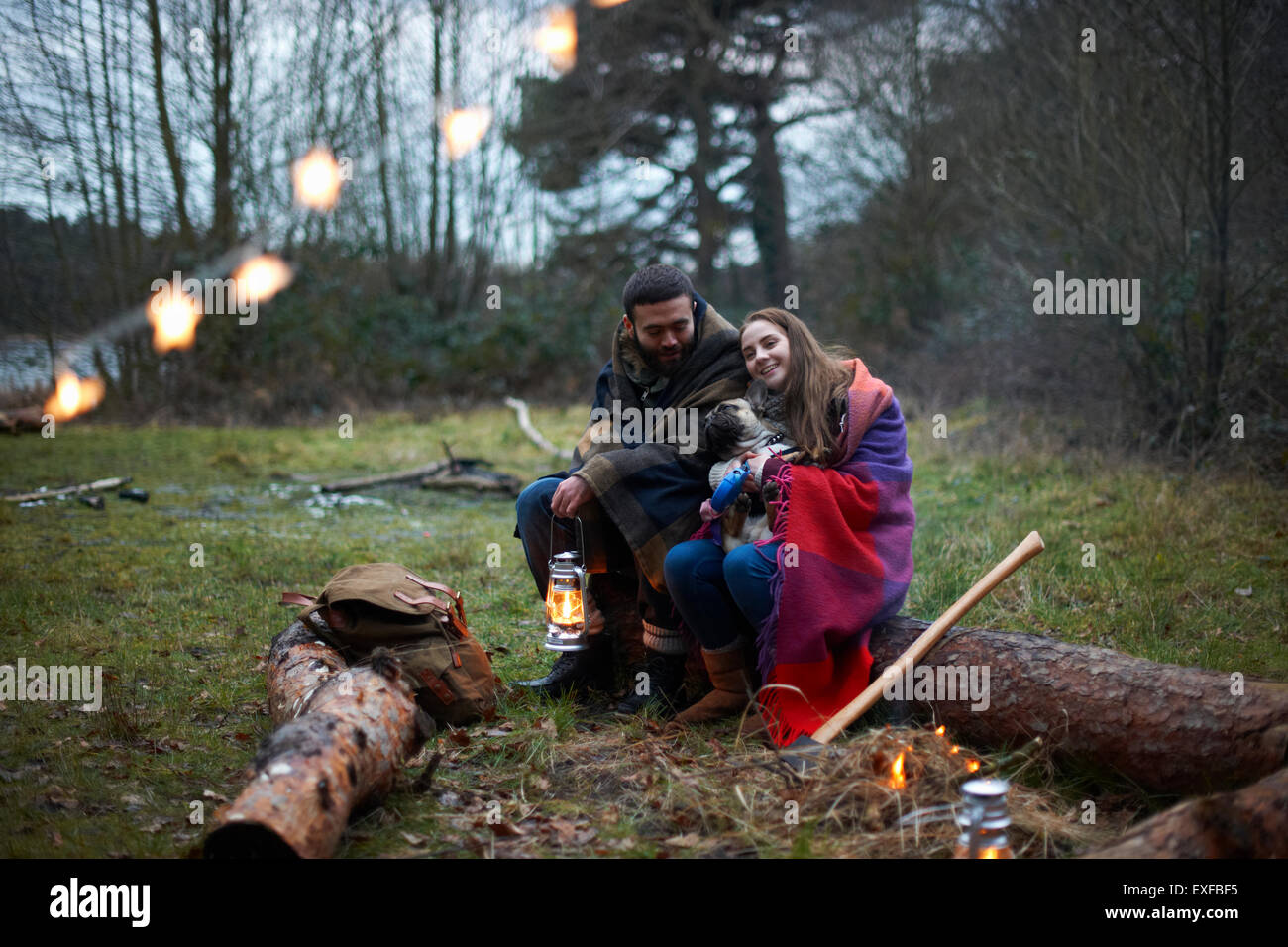 Camping Pärchen mit Hund in Decke im Wald gehüllt Stockfoto
