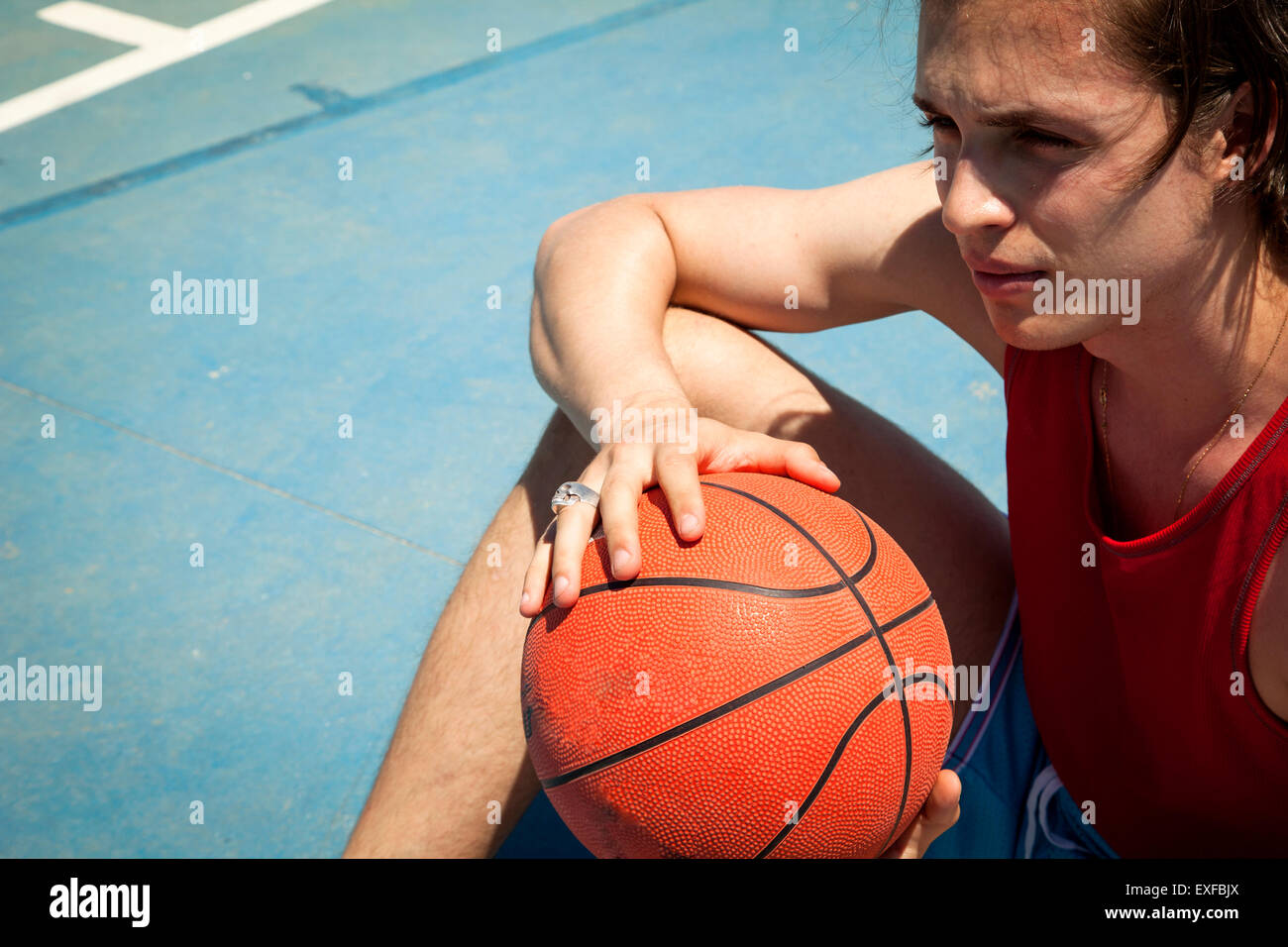 Junge männliche Basketball-Spieler sitzen am Basketballplatz Stockfoto
