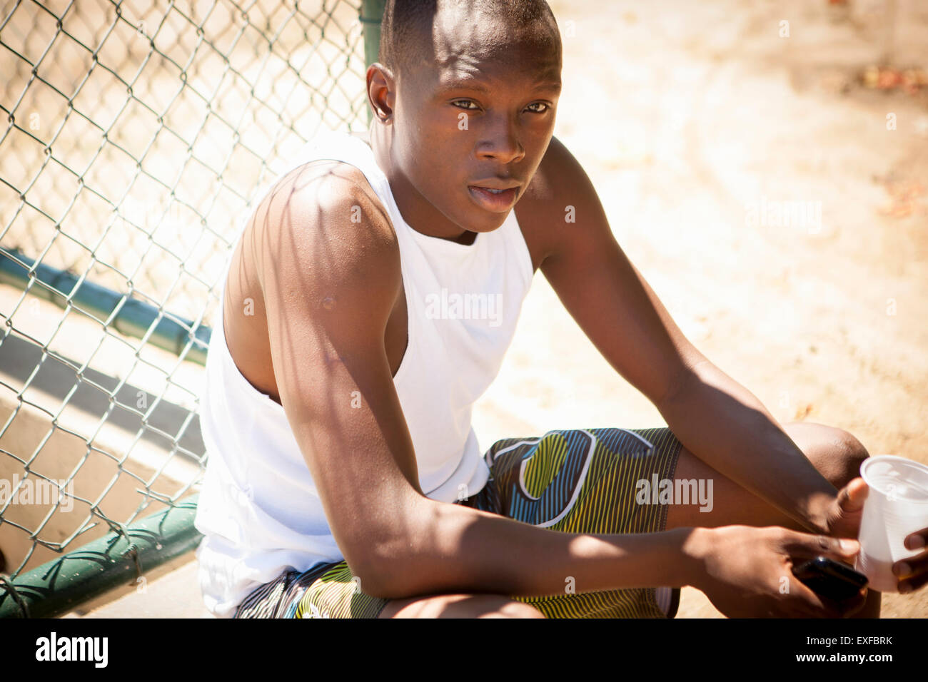 Porträt des jungen männlichen Basketballspieler mit Smartphone und Trinkwasser Stockfoto