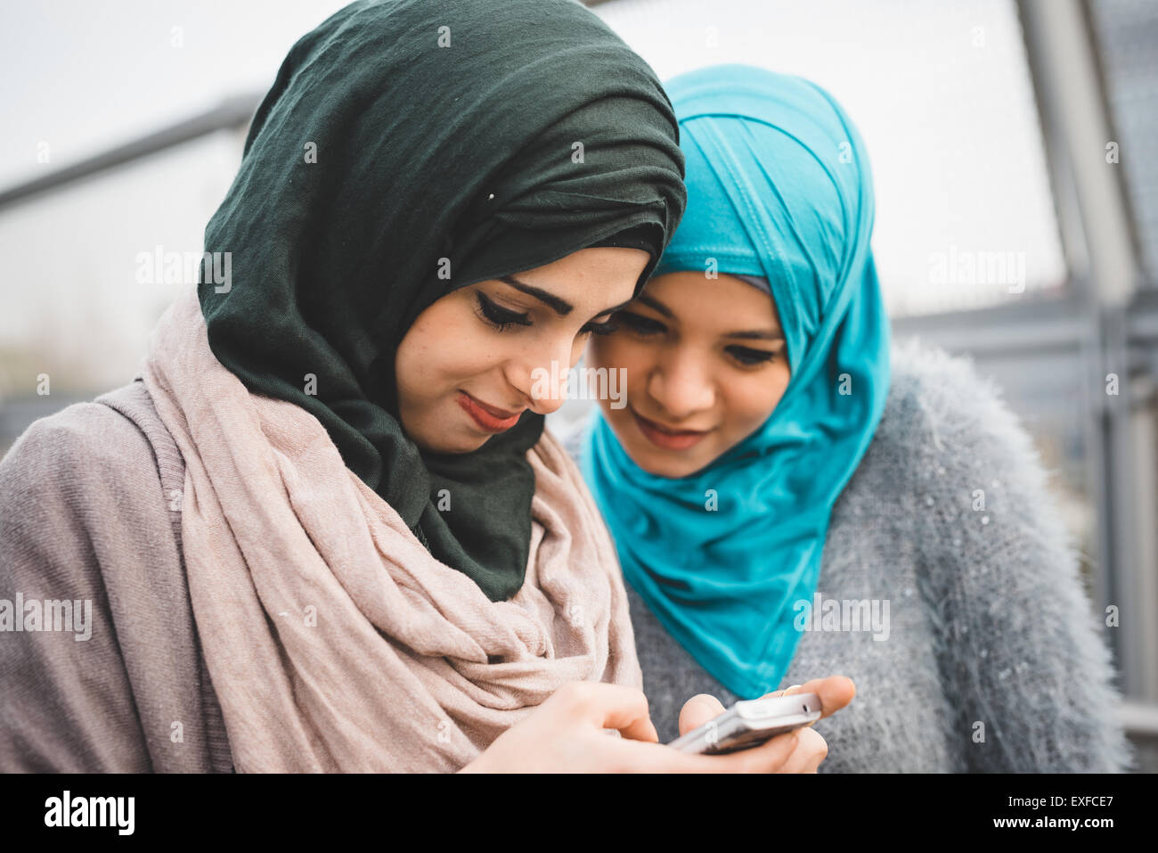 Zwei junge Freundinnen lesen Smartphone Texte auf Park-Weg Stockfoto