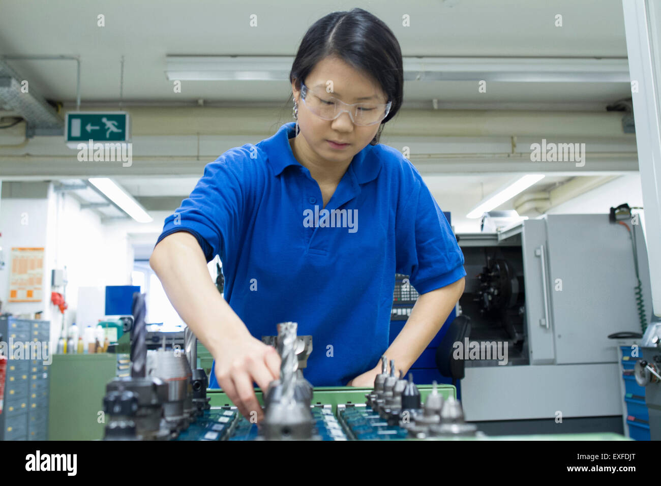 Junge Frau Metallkomponenten in industriellen Workshop auswählen Stockfoto