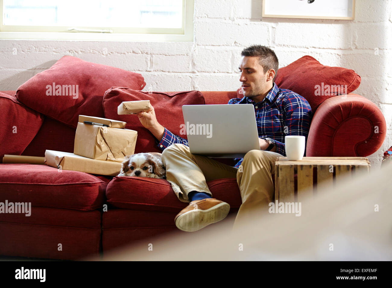 Mitte erwachsenen Mannes Vorbereitung Parzellen auf Sofa im Bild Händler showroom Stockfoto