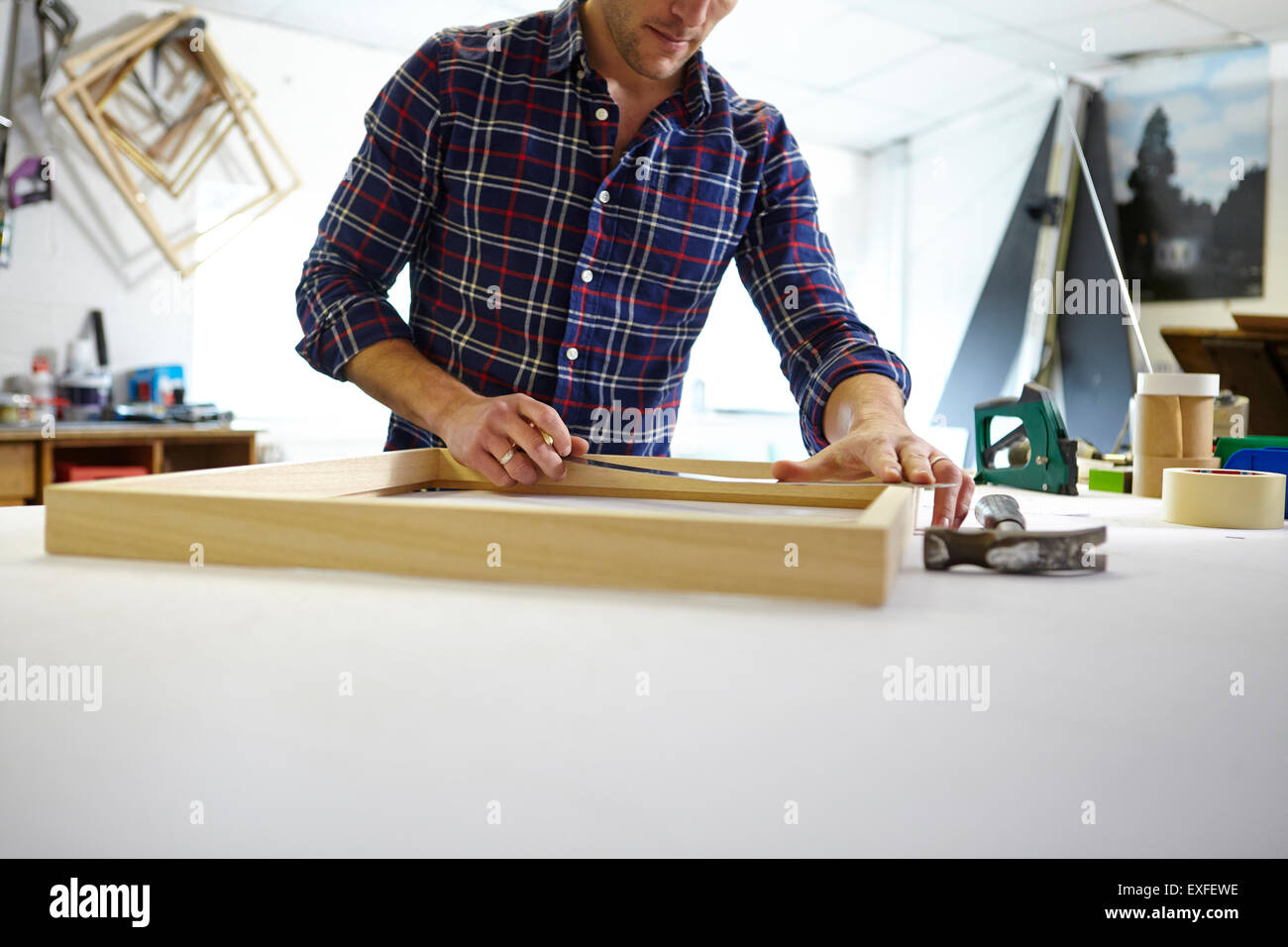 Mitte erwachsenen Mannes Messung Frame auf Werkbank in Bild Einrahmer Werkstatt Stockfoto