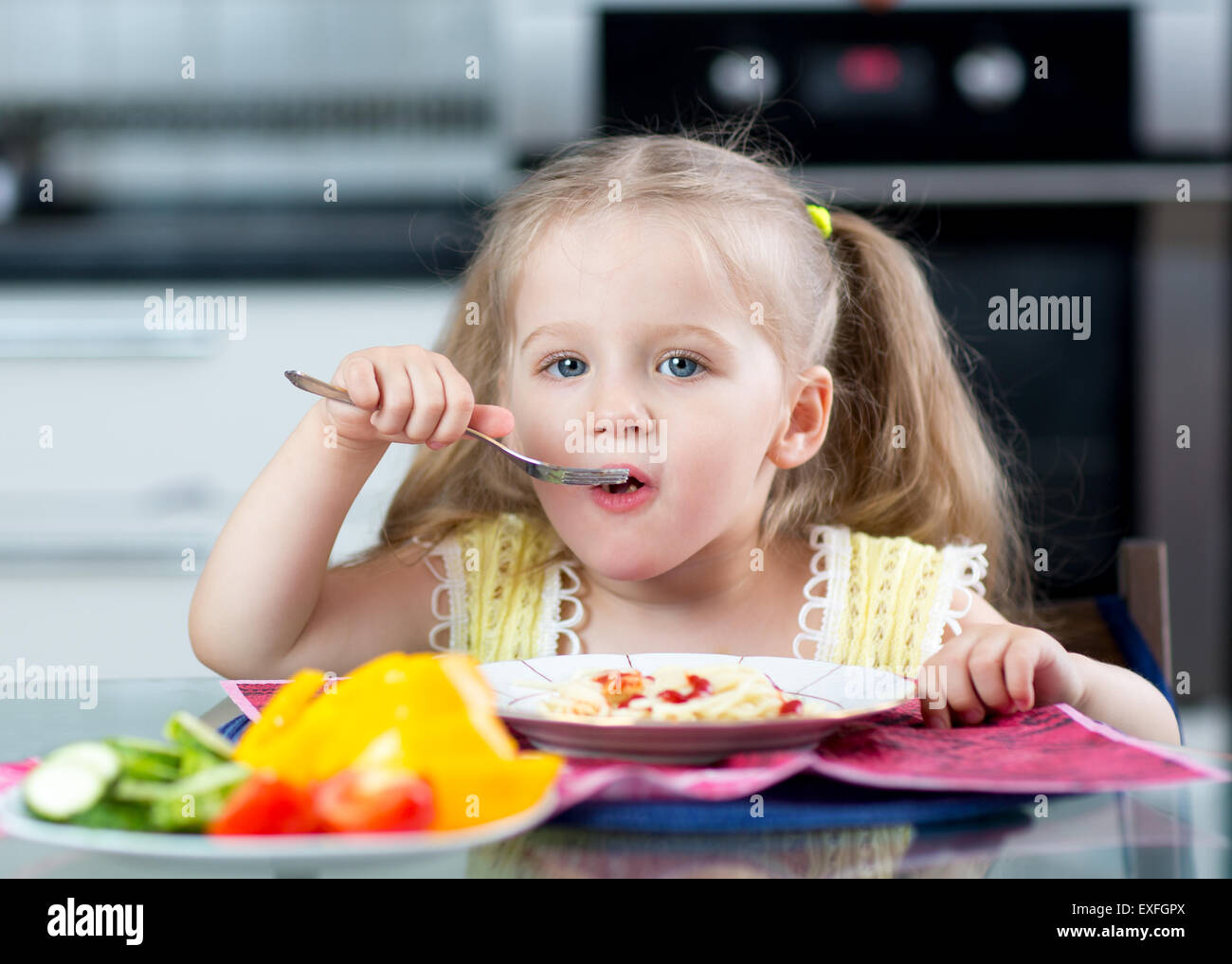 Kinder essen Spaghetti mit Gemüse im Kindergarten oder zu Hause Stockfoto