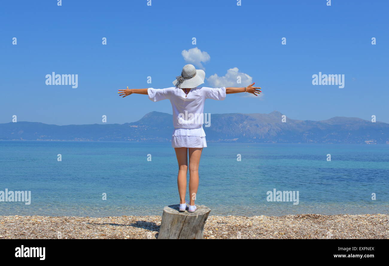 Junge Frau, Blick auf die Berge über dem Meeresspiegel mit weit geöffneten Armen an einem sonnigen Sommertag Stockfoto