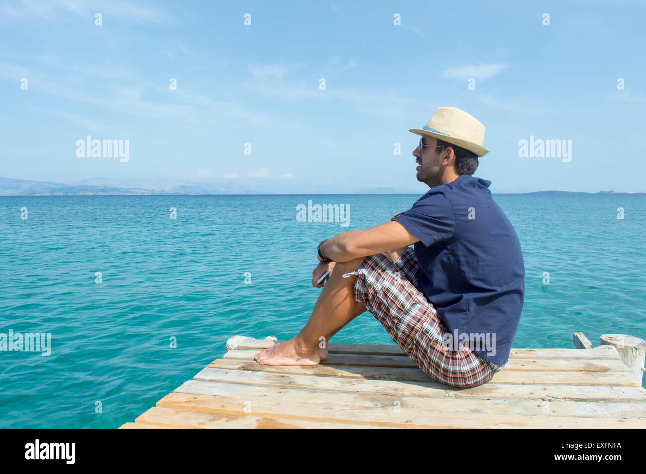 Junger Mann auf der Anklagebank sitzen und mit Blick auf Meer Stockfoto