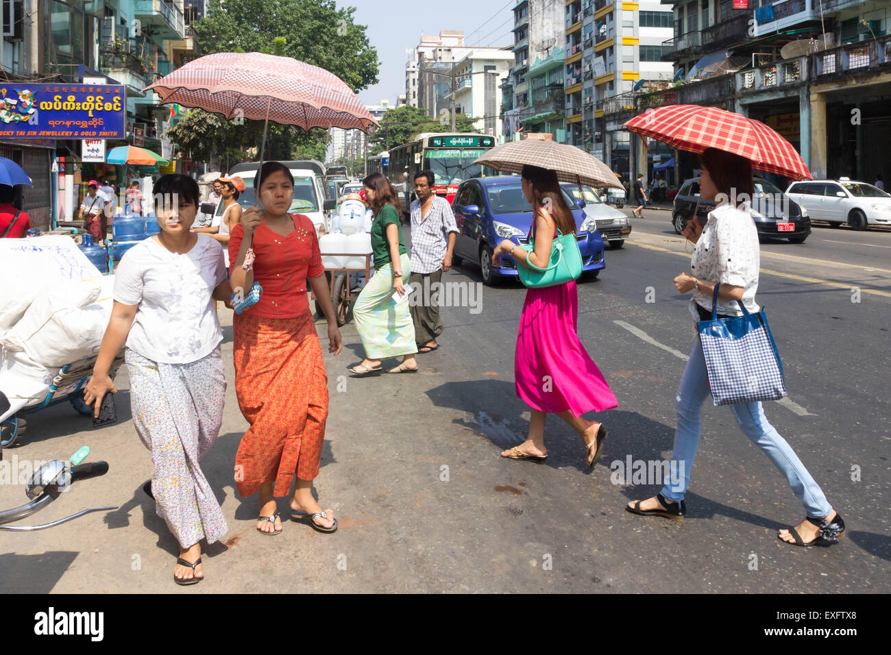 Yangon, Myanmar-Mai 5. 2014: Menschen, die die Straße überqueren. Menschen verwenden häufig Sonnenschirme sind Regenschirme, die Sonne zu schützen. Stockfoto