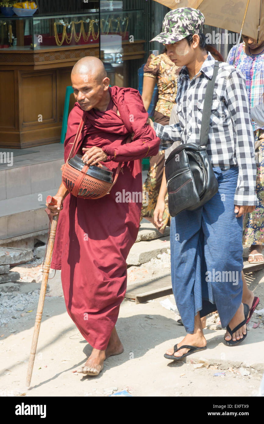 Yangon, Myanmar-Mai 5. 2014: ein Mann hilft einen blinden Mönch auf der anderen Straßenseite. Mönche sind ein alltäglicher Anblick in der Stadt. Stockfoto