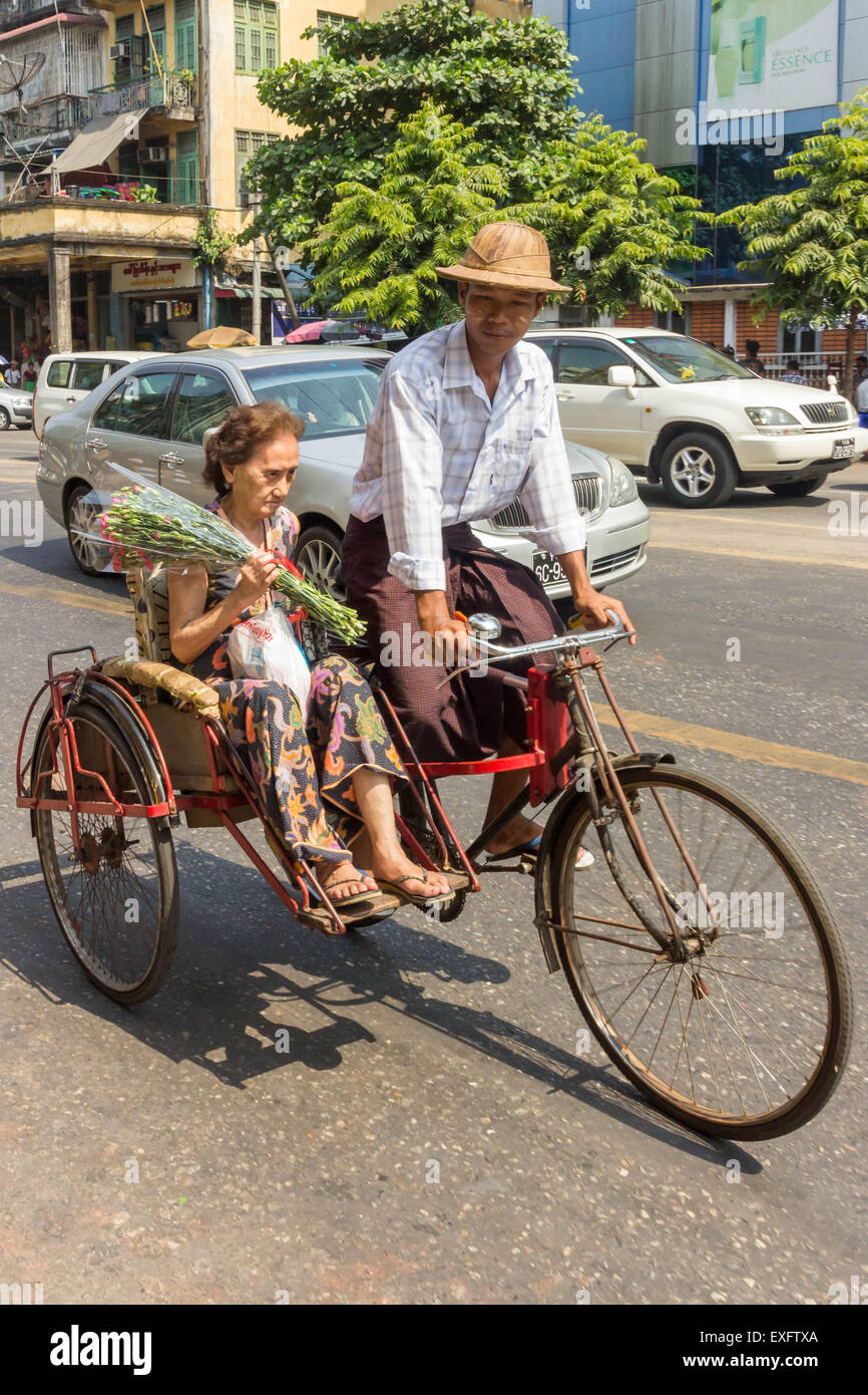 Yangon, Myanmar-Mai 5. 2014: eine Rikscha trägt einen Passagier zu ihrem Ziel. Diese Form des Transports ist nach wie vor verbreitet. Stockfoto