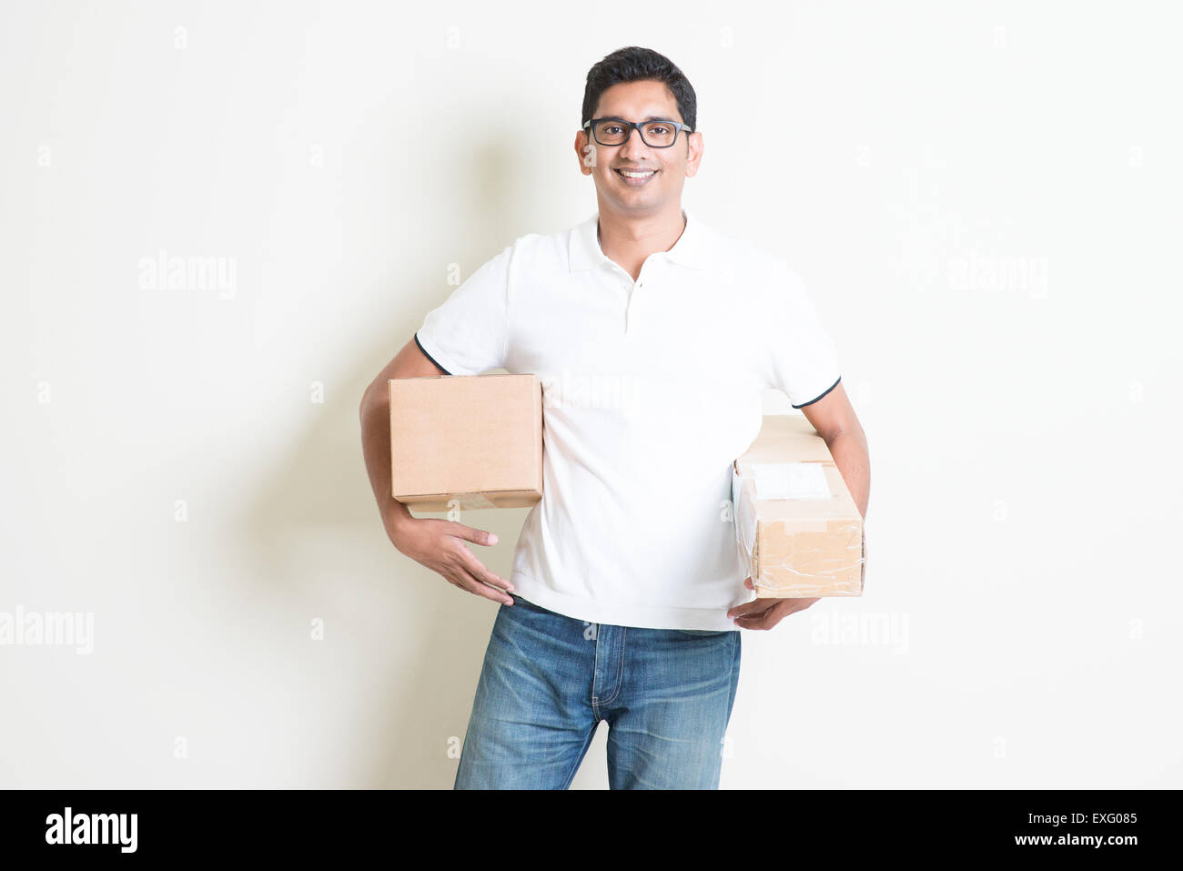 Kurier-Lieferung-Service-Konzept. Glücklicher indischer Mann erhielt braune Boxen, stehend auf einfarbigen Hintergrund mit Schatten. Asiatische handsom Stockfoto