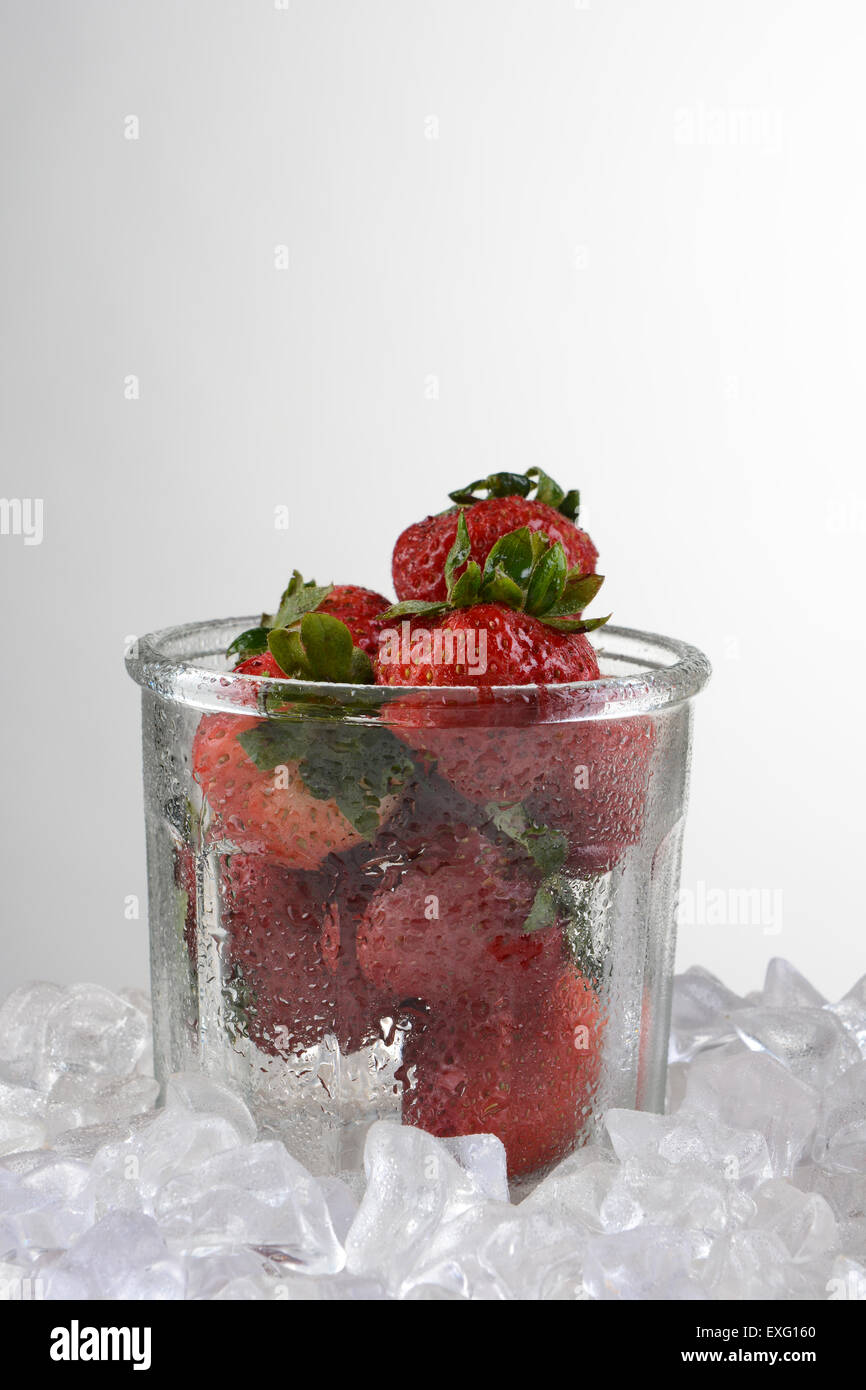 Eine altmodische Glas mit frisch gepflückten Erdbeeren von zerstoßenem Eis umgeben. Hochformat auf ein Licht auf dunklem Hintergrund Witz Stockfoto