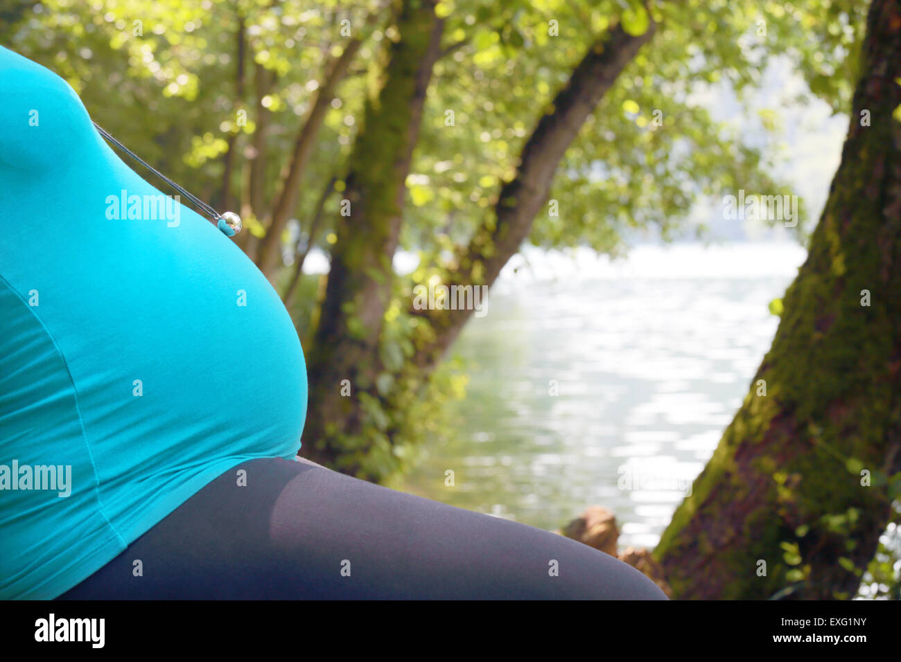 Nahaufnahme der Bauch einer schwangeren Frau Entspannung in der Natur in der Nähe von einem See in einem Holz Stockfoto
