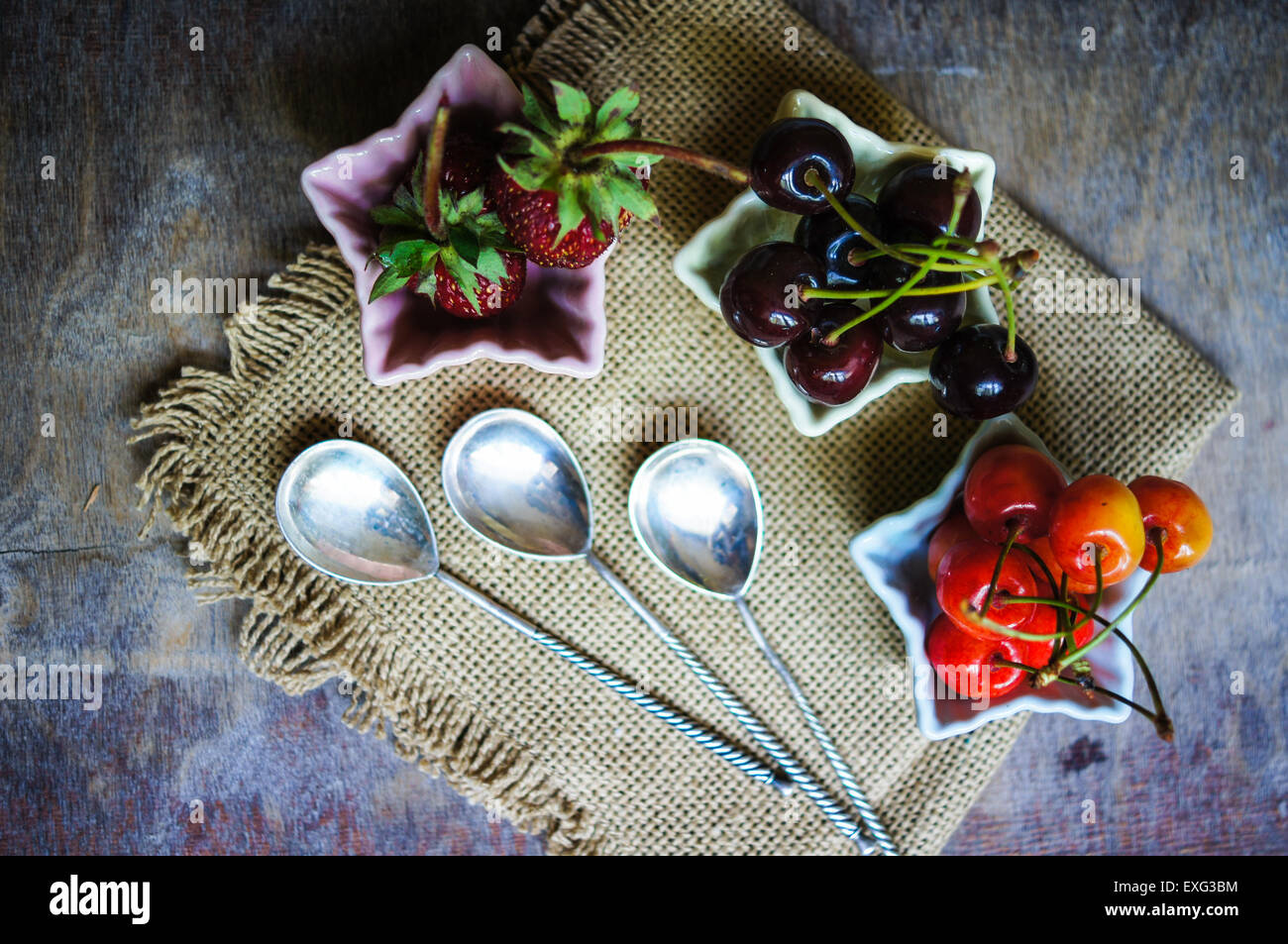Drei sternförmige Schalen mit frischen saisonalen Früchten - Erdbeere und zwei Arten von Kirschen Stockfoto