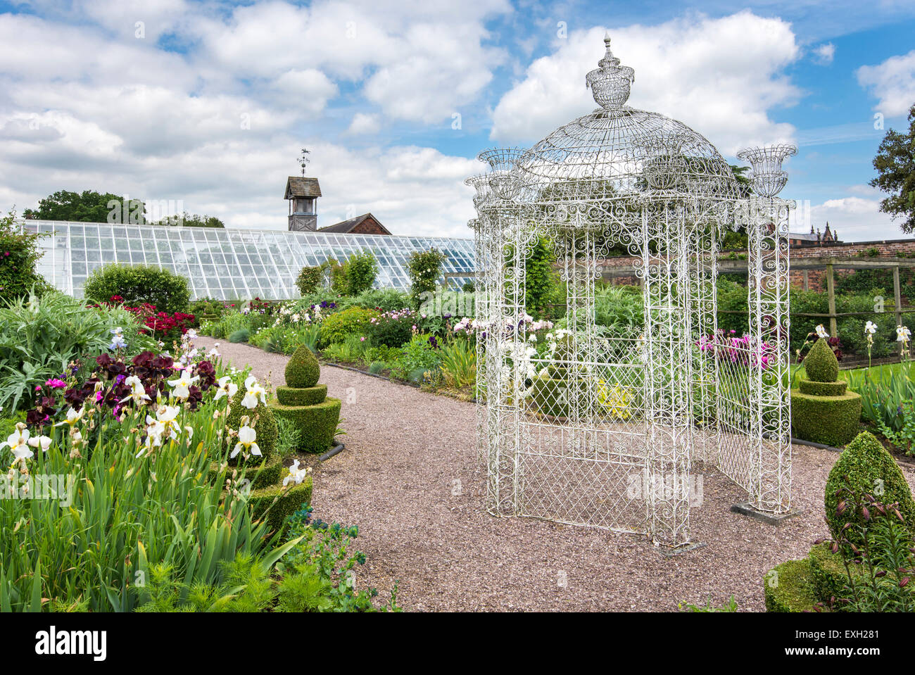 Reich verzierte Draht Pavillon umgeben von bärtigen Iris, Pfingstrosen und Formschnitt Arley Hall Gardens in Cheshire, England. Stockfoto