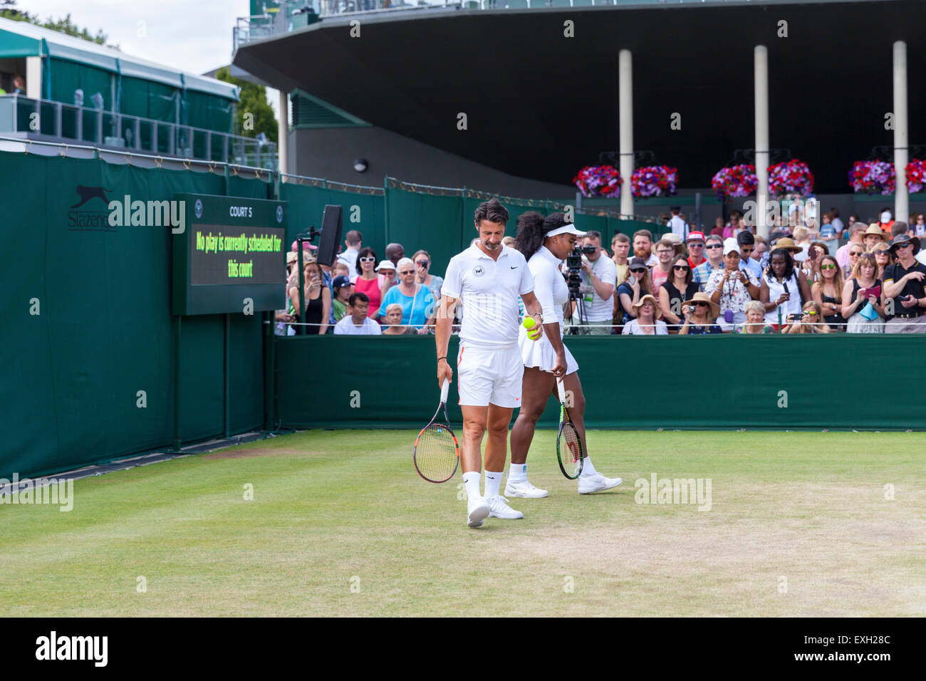 Serena Williams erwärmt sich für das Spiel auf Platz Nr. 5, geholfen durch Trainer Patrick Mouratoglou, während der Wimbledon Championships 2015 Stockfoto