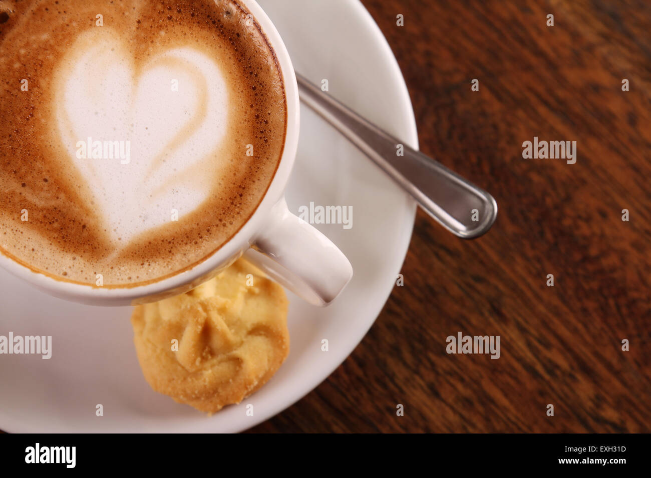 Köstlich aromatischen Cappuccino in einer weißen Porzellantasse mit einem Keks auf der Seite auf einem Holztisch. Bild enthält Textfreiraum. Stockfoto