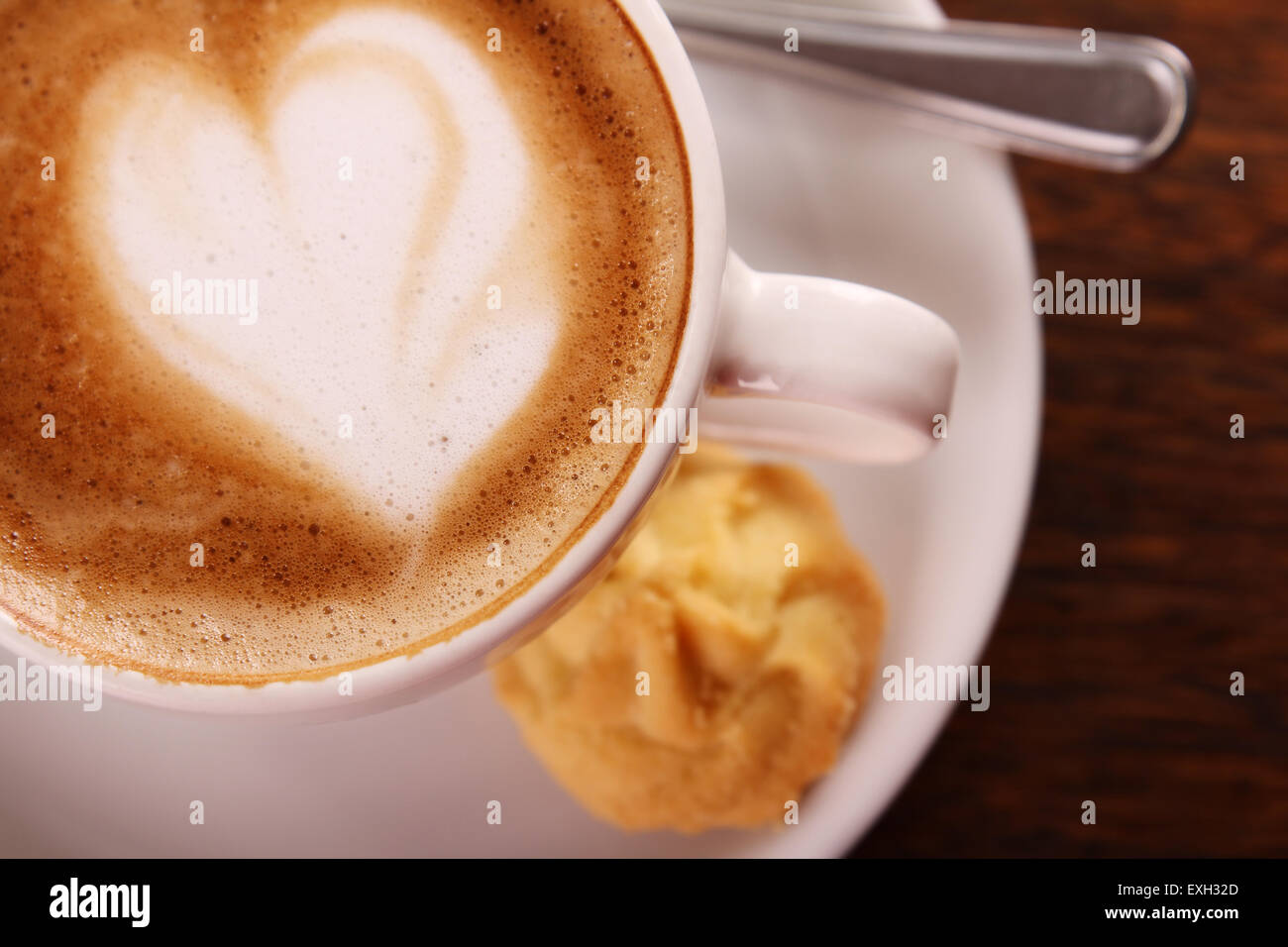 Köstlich aromatischen Cappuccino in einer weißen Porzellantasse mit einem Keks auf der Seite auf einem Holztisch. Bild enthält Textfreiraum. Stockfoto