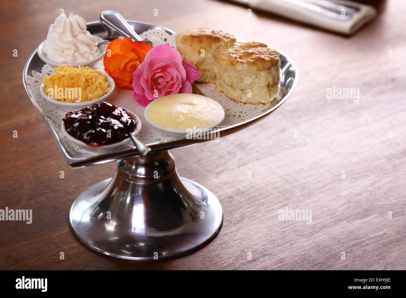 Köstliche Butter Gebäck auf einem Tablett Silber in Herzform mit Rosen Käse Sahne serviert und Marmelade auf einem Holztisch bewahrt. Stockfoto