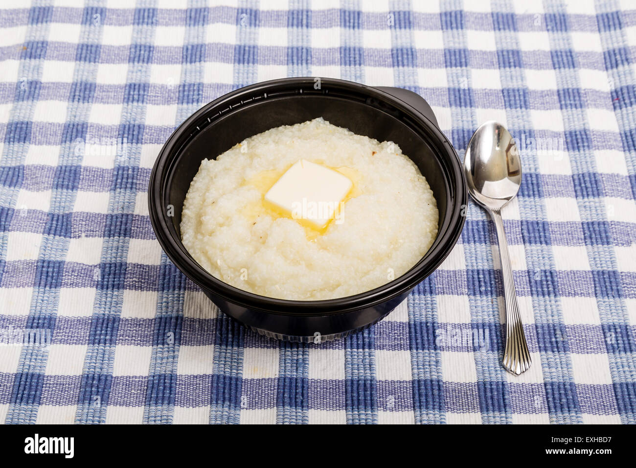 Eine schwarze Schale mit weißen Mais Grütze und schmelzende Butter auf einem blau karierte Tuch Stockfoto